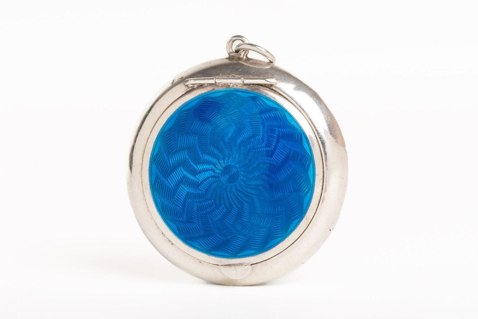 This stunning Art Deco 1930's blue guilloche enamel and silver gilt mirror compact/pendant is made by well known Birmingham jewellers: Crisford and Norris. The front cover of this beautiful piece is decorated in a blue guilloche enamel with a