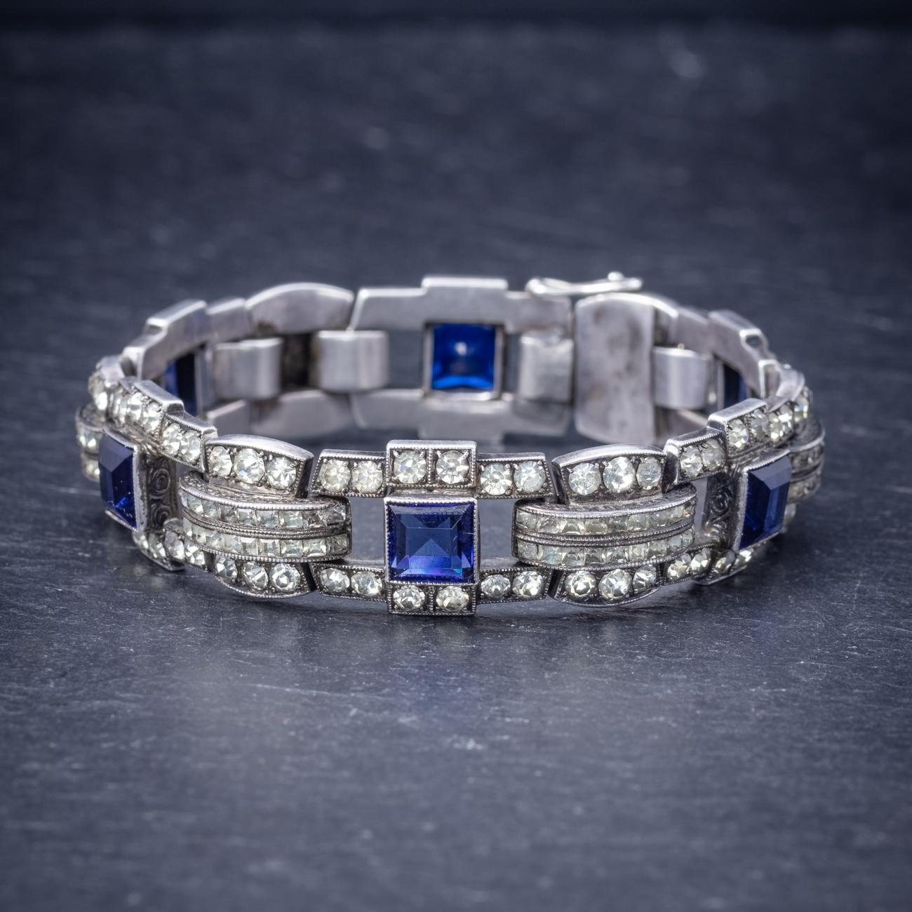 A beautiful Art Deco bracelet made up of robust Silver links with a typical Art Deco geometric design. The piece is decorated in square cut Bristol blue Paste stones which have the deep colouring of Sapphires and are complemented by smaller white