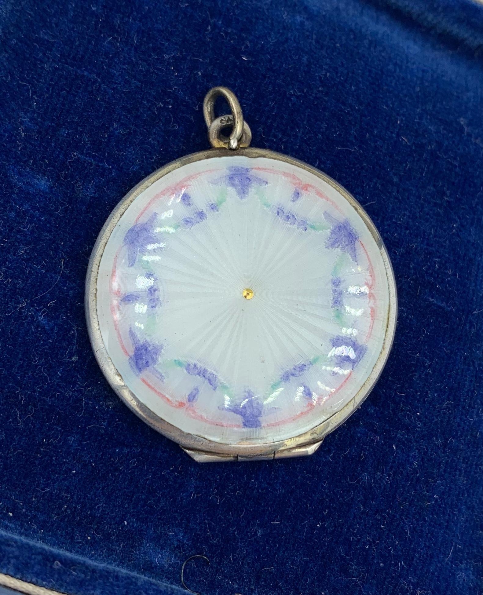 This is a wonderful Edwardian - Art Deco Locket Pendant with a gorgeous blue and pink enamel flower garland motif on a delicate pale blue-green Guilloche Enamel background over Sterling Silver.  The reverse of the locket has a guilloche engine