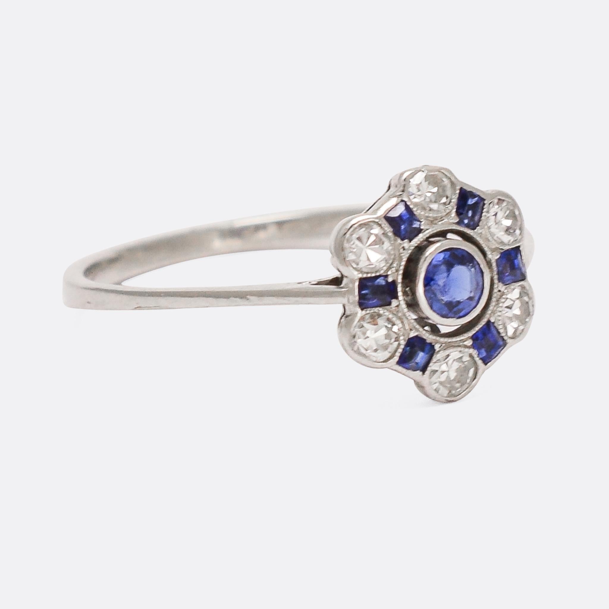 Incredibly pretty Art Deco sapphire and diamond cluster ring dating from the 1920s. It features six white diamonds, alternating with calibré cut sapphires to create a hexagonal halo around the central blue sapphire - all set in millegrain platinum