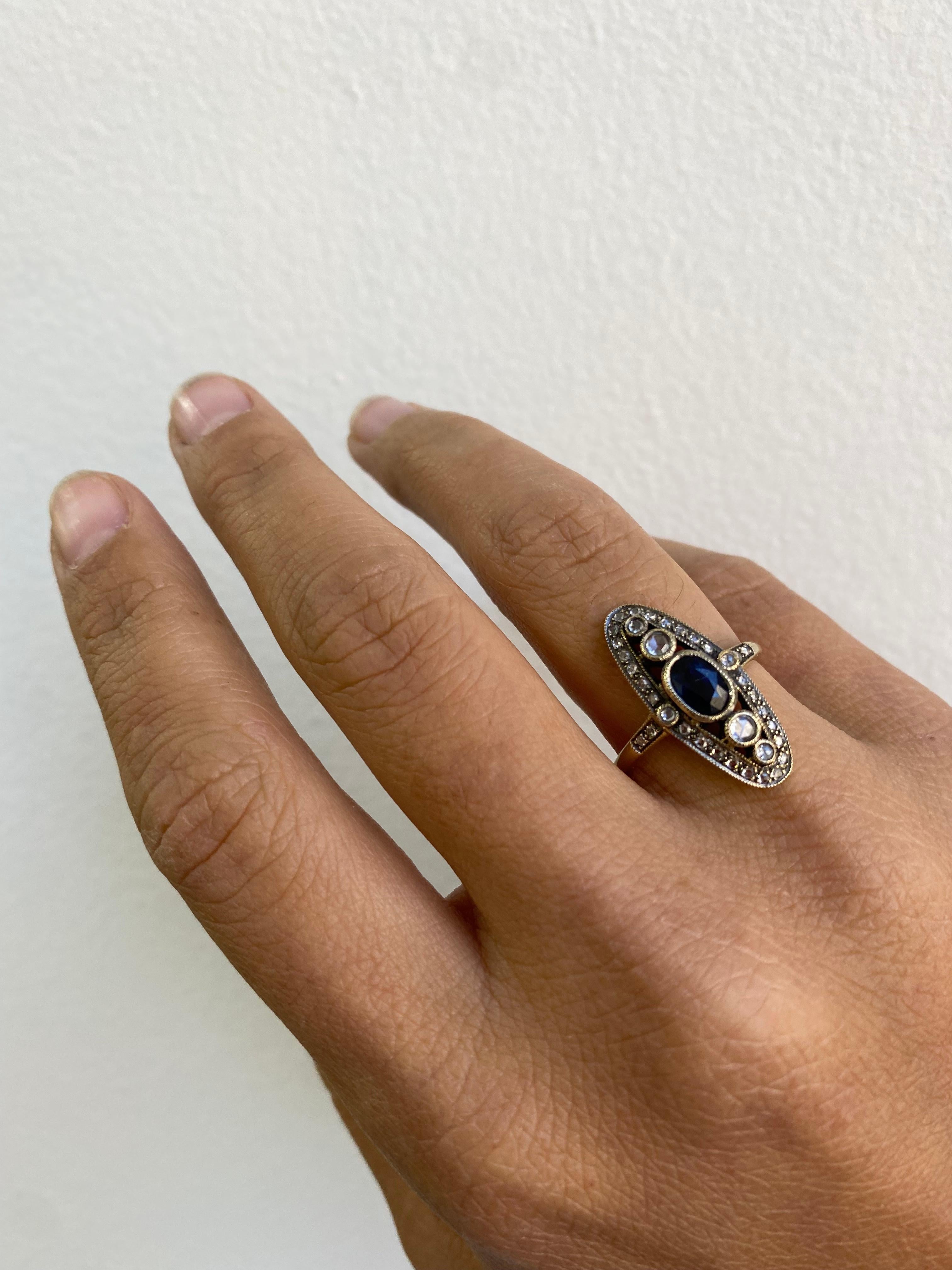 Langer ovaler Ring mit blauem Saphir und Diamanten 

Dieses elegante Art-Déco-Revival zeichnet sich durch einen ovalen blauen Saphir von 0,75 Karat in der Mitte aus, der mit goldfarbenen Diamanten im Rosenschliff und runden Diamanten im