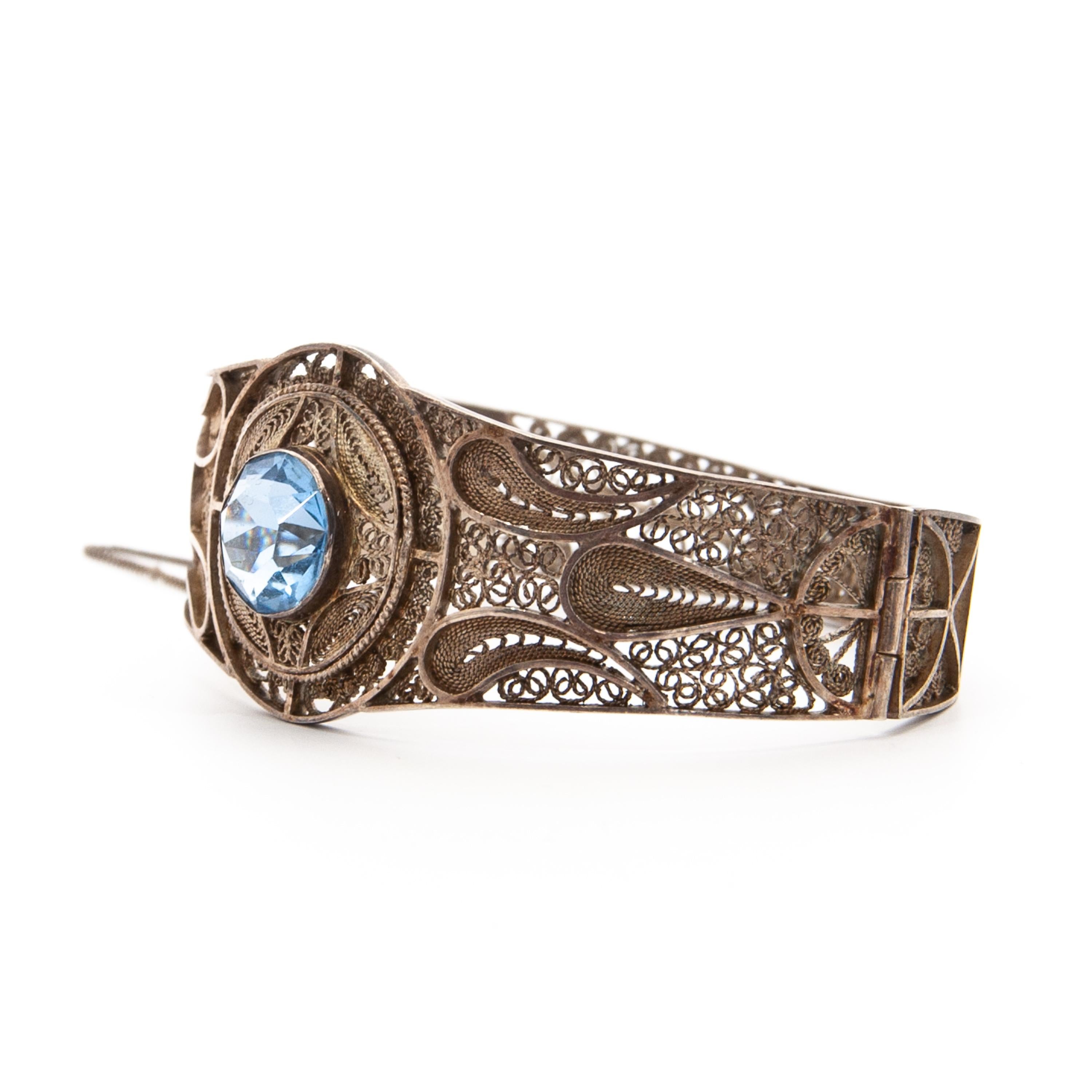 An Art Nouveau-style silver bangle bracelet set with a blue stone. This gorgeous handmade bracelet is made of genuine 835 silver, studded with one big blue stone in the center in aquamarine color. The filigree is very fine and delicate detailed,
