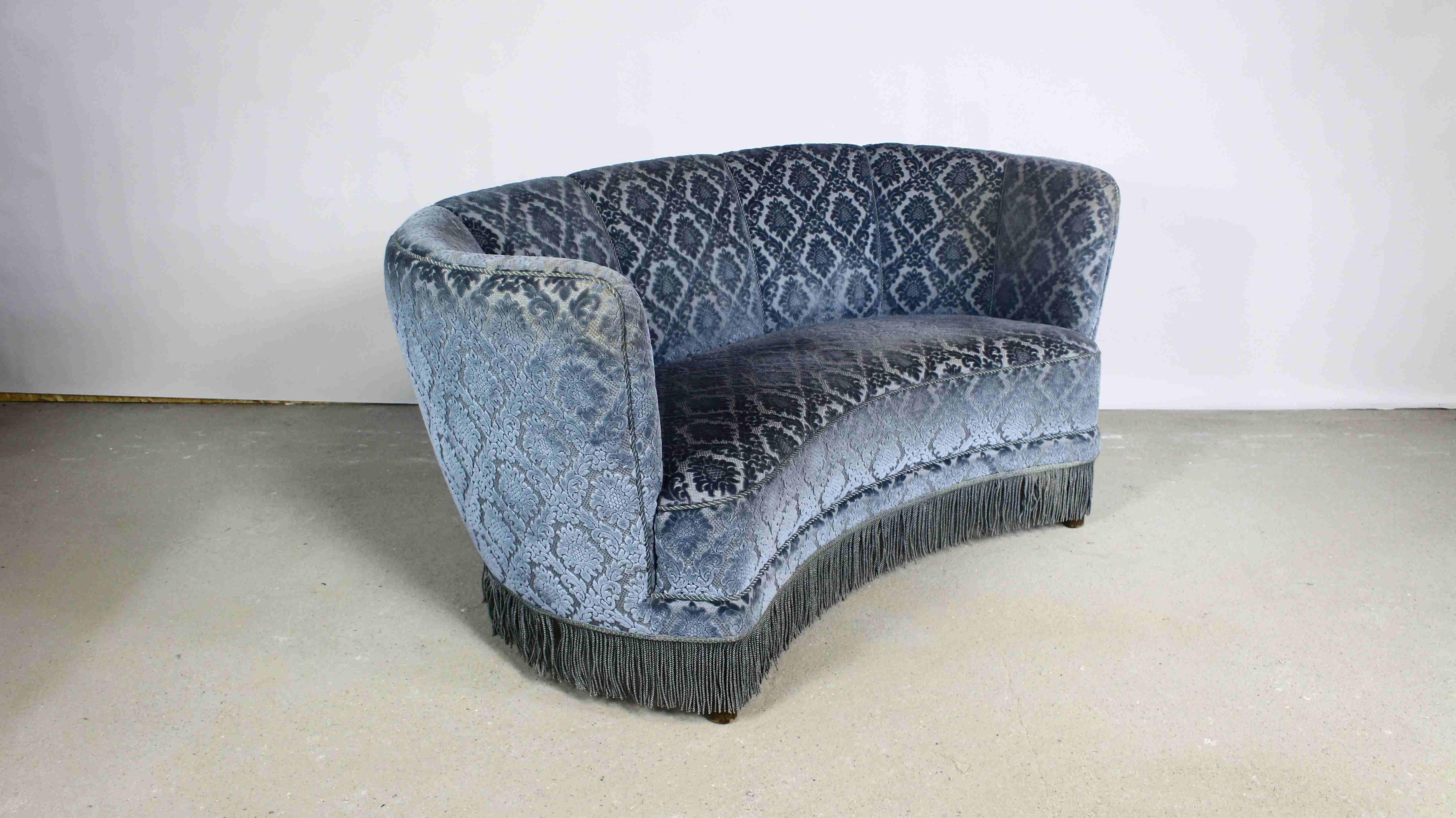 Un magnifique canapé rond de style art déco.
Tapissé de velours bleu avec un motif floral en relief.
Fabriqué au Danemark dans les années 1950.
Siège avec sangles et ressorts.
Les endroits éclaircis sur les tissus d'ameublement sont l'effet de la