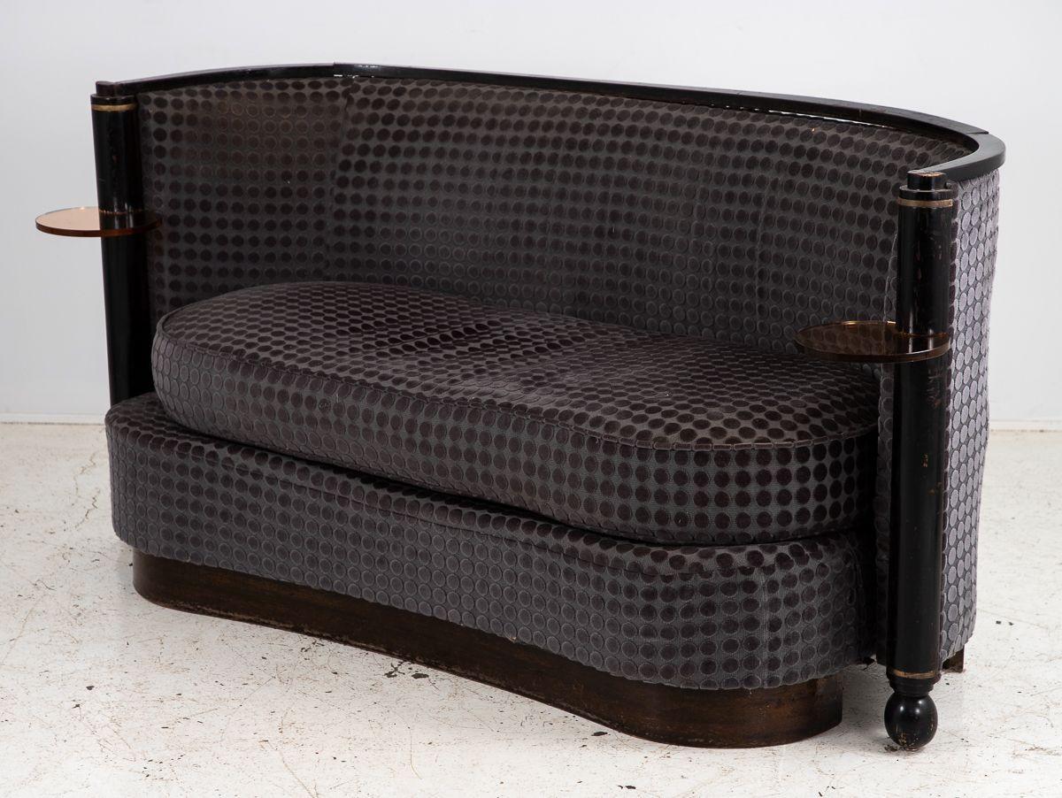 Ce remarquable canapé en velours Art déco français est une pièce rare et visionnaire qui présente un design en forme de rein sur une base à plate-forme avec quatre pieds de forme unique, deux ronds et deux rectangulaires. Le canapé est orné d'un