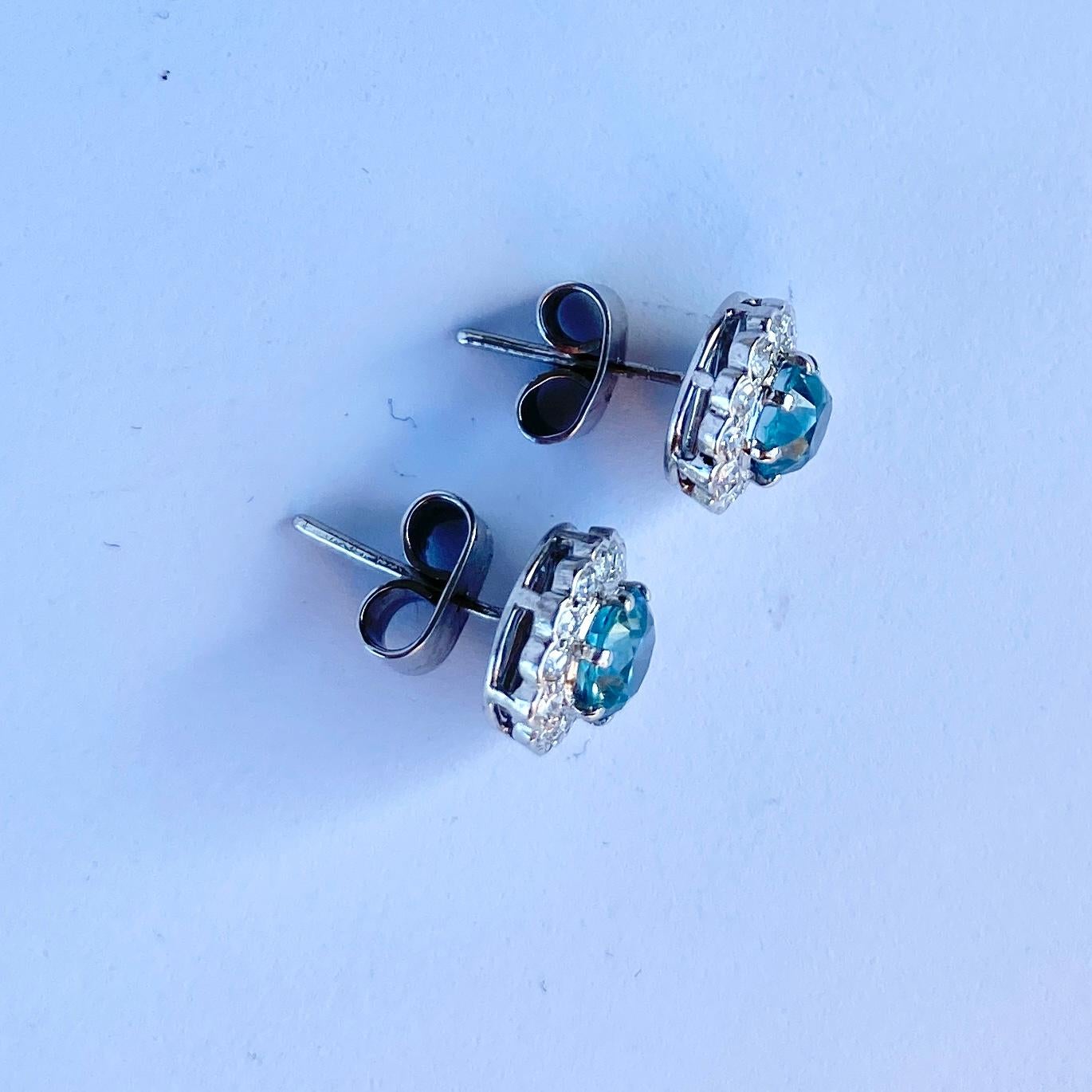 The gorgeous blue of these zircon stones is perfectly complimented by the halo of sparkling diamonds surrounding them. The zircon measures approximately 75pts each and the diamonds total 15pts per earring. 

Cluster Diameter: 9mm 

Weight: 3.3g
