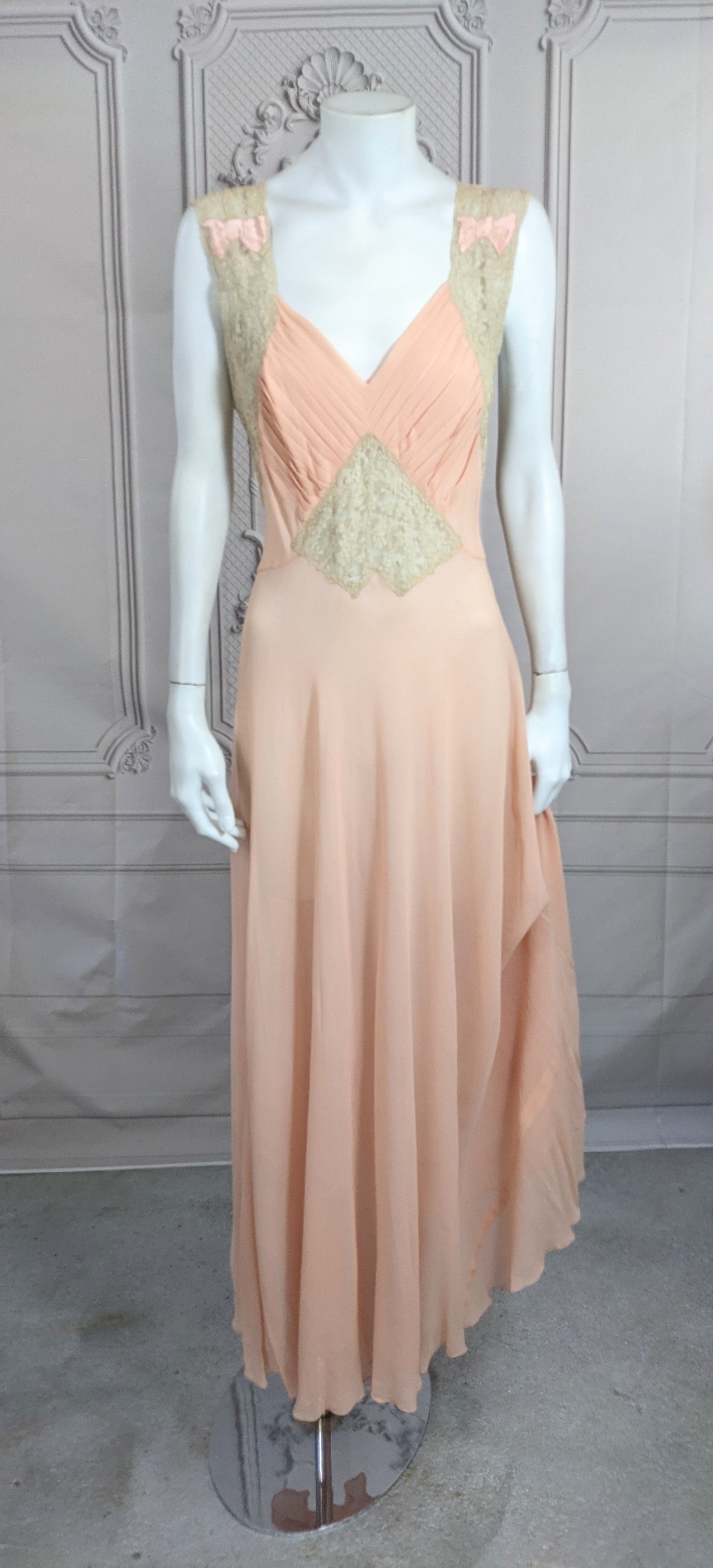 Art Deco blush pink silk crepe chiffon slip dress with pleated bodice and sheer hand made Alencon lace shoulder straps and triangular midriff insert. Satin bow inserted appliques on shoulder, lovely hand made detailing. Excellent Condition.  
  Size