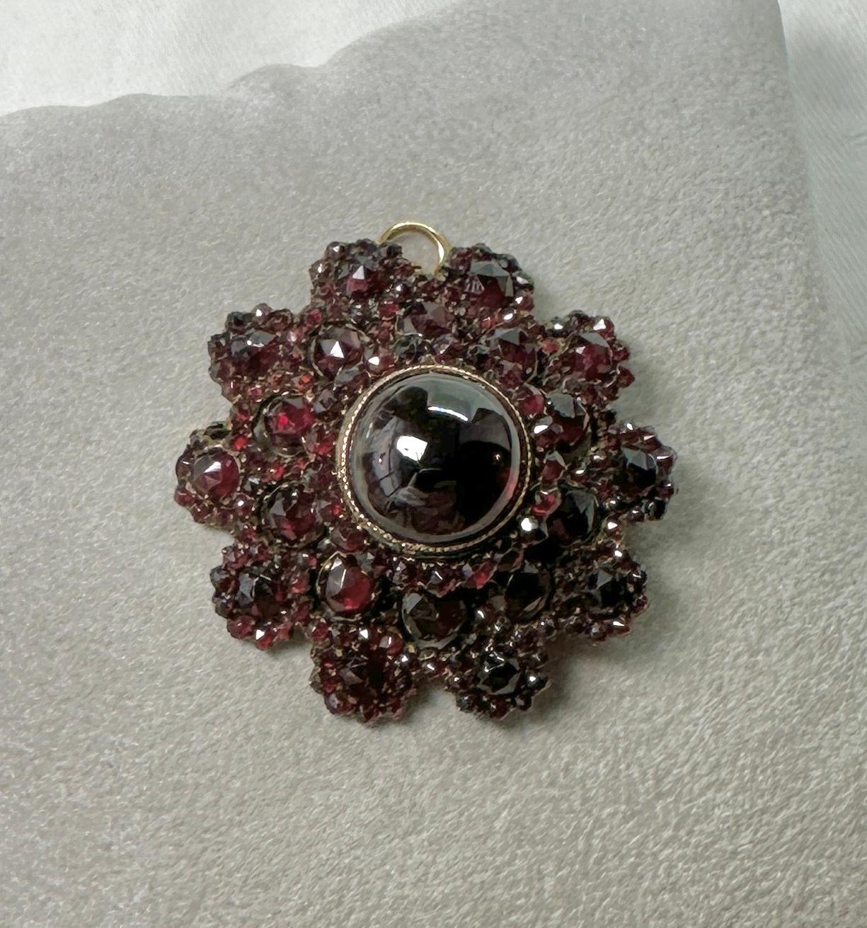 This is a gorgeous Antique Art Deco - Victorian Pendant or Brooch set with the most wonderful 1/2 inch Garnet Cabochon in the center surrounded by sparkling blood red Bohemian Garnets in three layers.  The garnets are full of radiant sparkle and