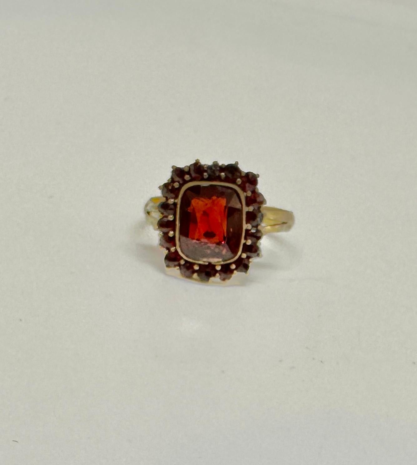 Dies ist eine wunderschöne frühe antike viktorianische - Art Deco Bohemian Granat Ring mit einem atemberaubenden rechteckigen facettierten blutroten Granat umgeben von einem Halo von runden Granaten.  Die Granate sind in Silber vergoldet, wie es in