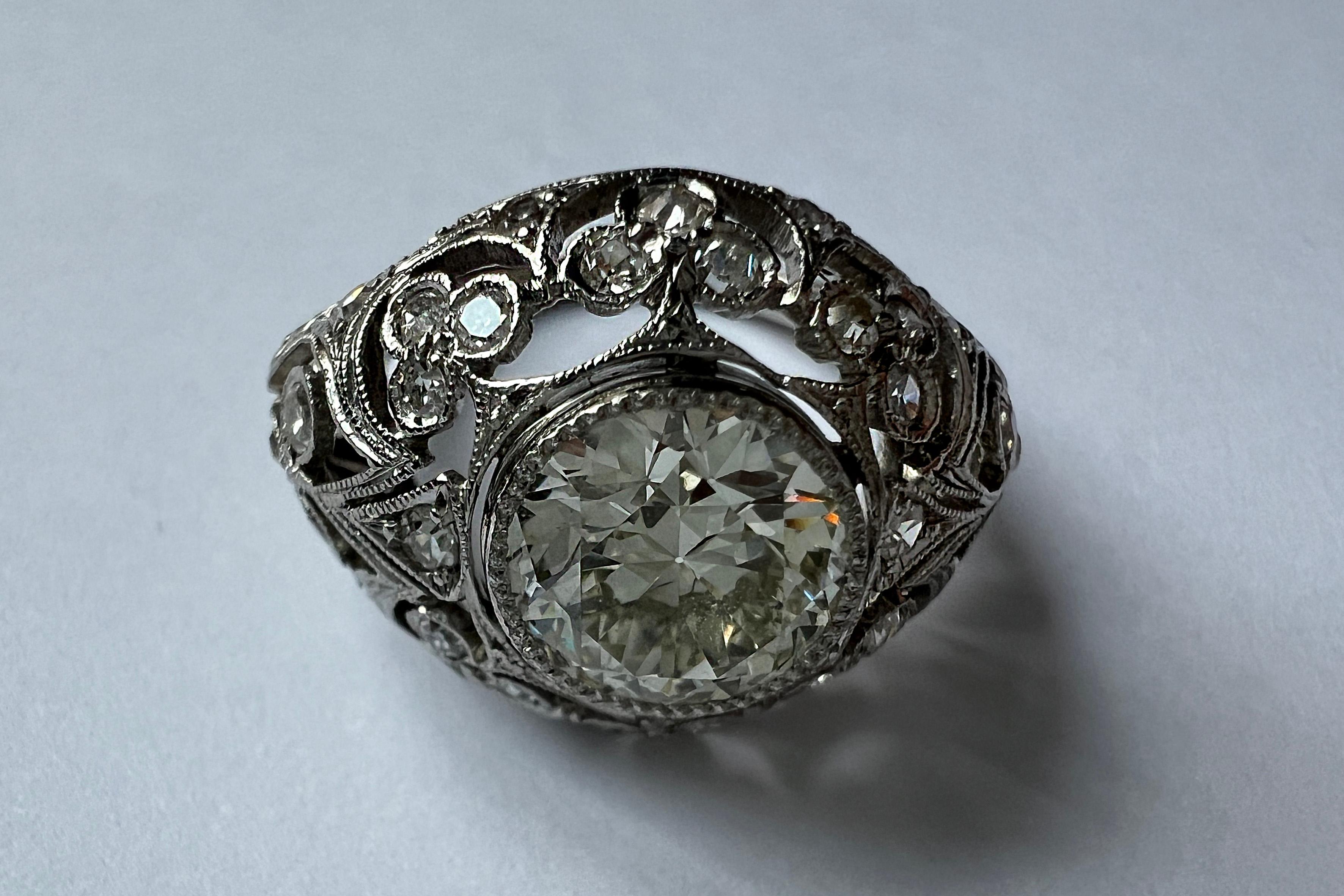 Art Deco Original Bombe' Platinum Dinner ring with diamonds, an exquisite testament to the glamour of a bygone era. Adorned with diamonds, the central old-cut round stone, boasting an approximate weight of 1.70 ct., takes center stage, surrounded by