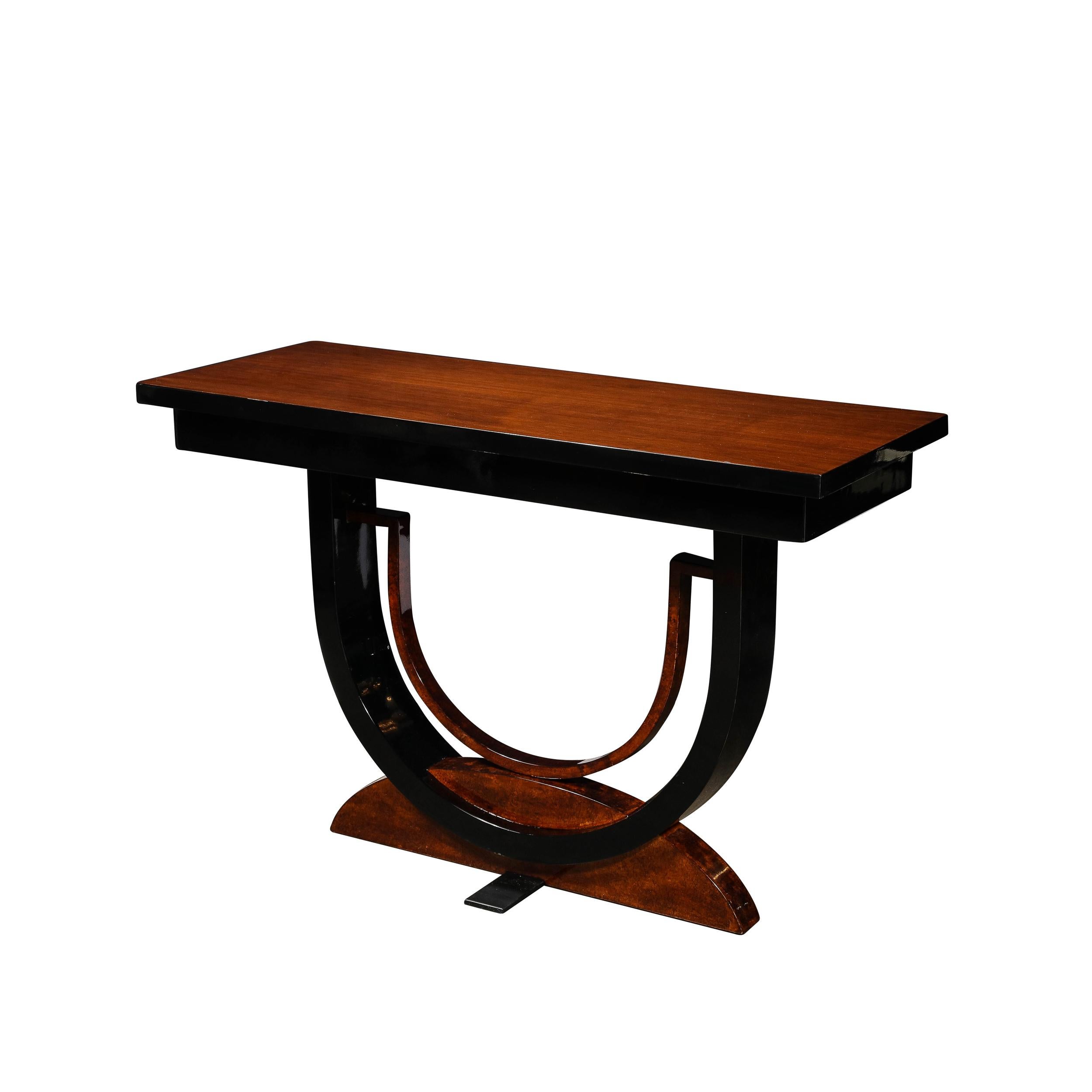 This Streamline Machine Age Art Deco Console Table is a stunning and sophisticated piece, powerfully utilizing the motifs of the Art Deco era in a stimulating and effortless geometric balance. Rendered in Bookmatched and Burled walnut with Black