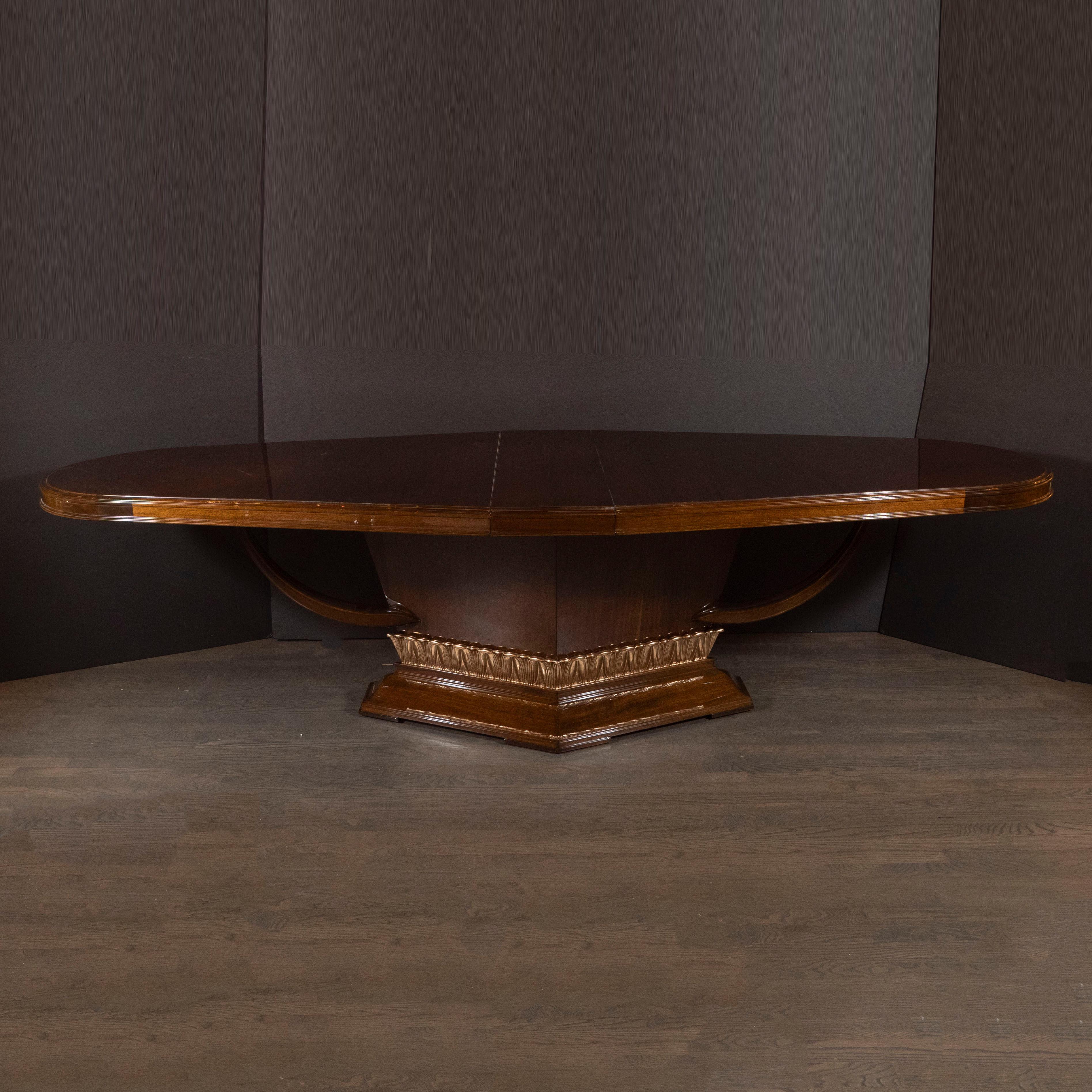 This stunning high style Art Deco dining table was realized in France, circa 1940. It features a bookmatched mahogany elongated ovoid top- exhibiting a beautiful natural grain- with streamlined supports on each side. Additionally, the polygonal base
