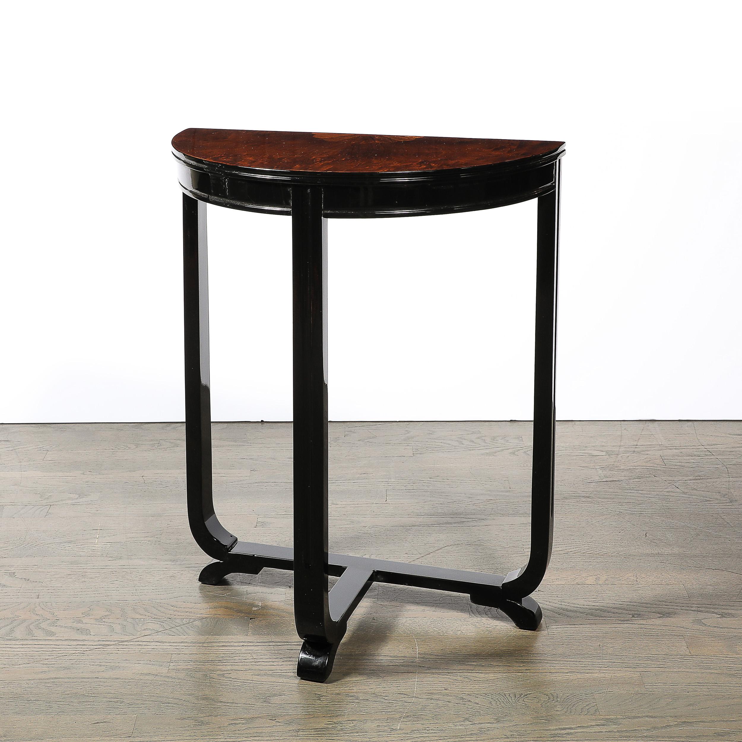 This beautifully crafted Art Deco Demilune Console Table W/Exotic Sunburst Inlaid Wood Motif in Book-Matched Walnut & Black Lacquered Supports originates from the United States, Circa 1930. Features three fluted supports, one on either side near the