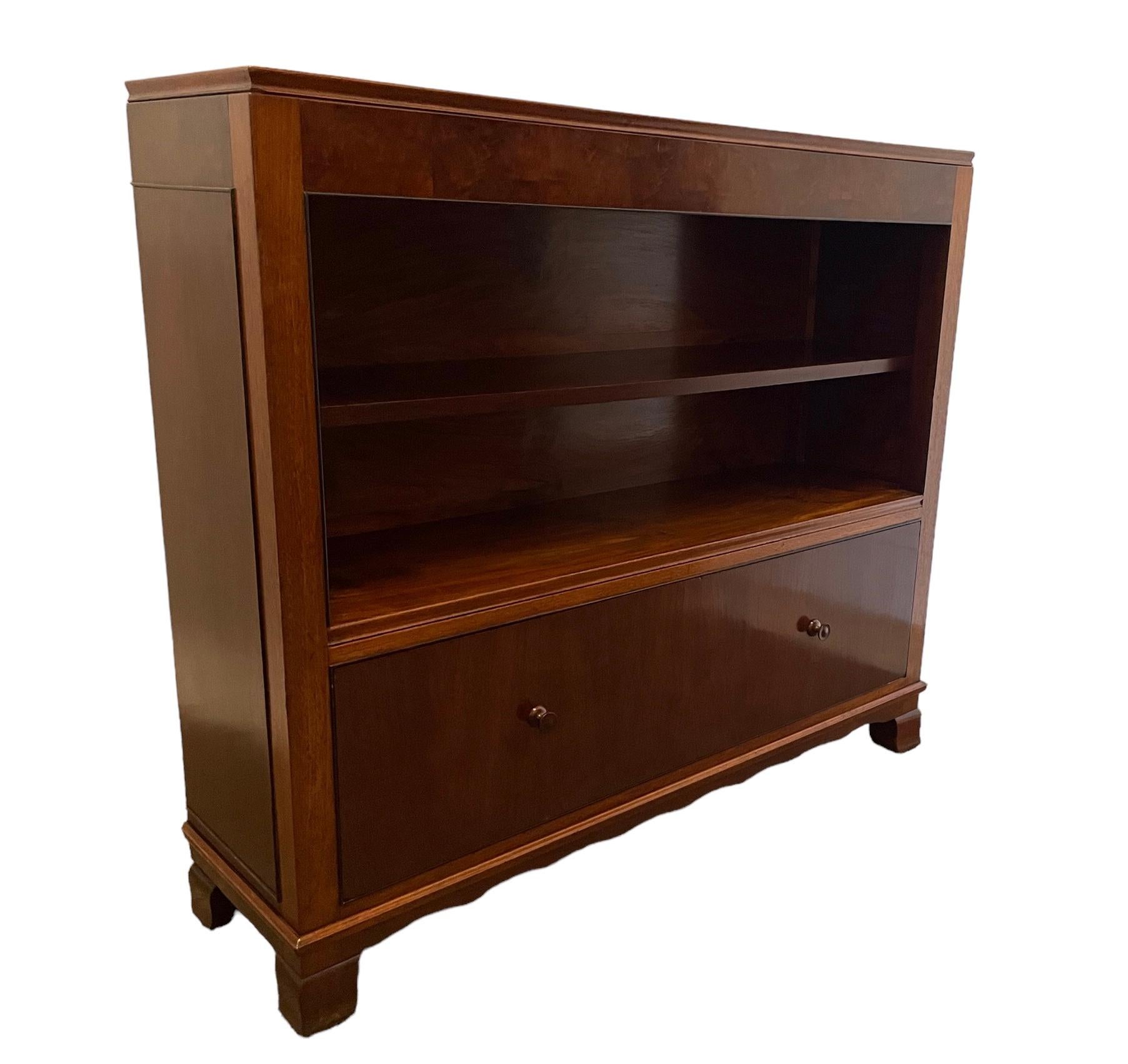 A quality Art walnut cabinet/bookcase by Maurice Adams. With two open shelves and a deep drawer below. Makers label to the back. A highly regarded company who designed and produced items for the upper class and aristocracy. 
This item features on