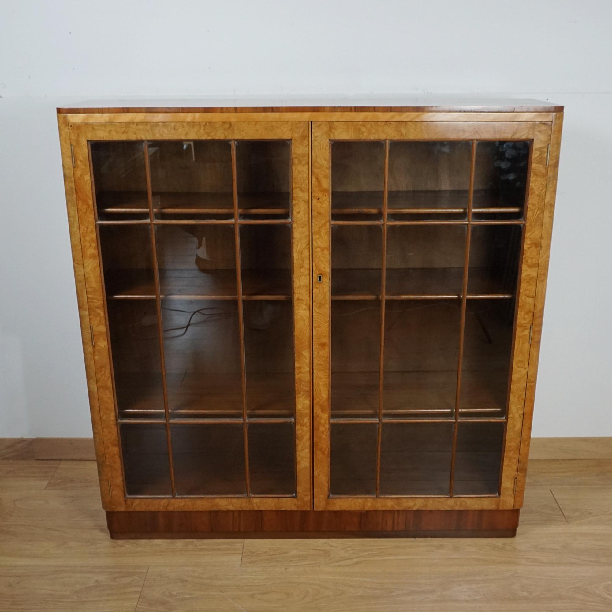 Una libreria in vetro Art Deco. Impiallacciato in radica di olmo e noce figurato con interno rivestito in mogano. 
