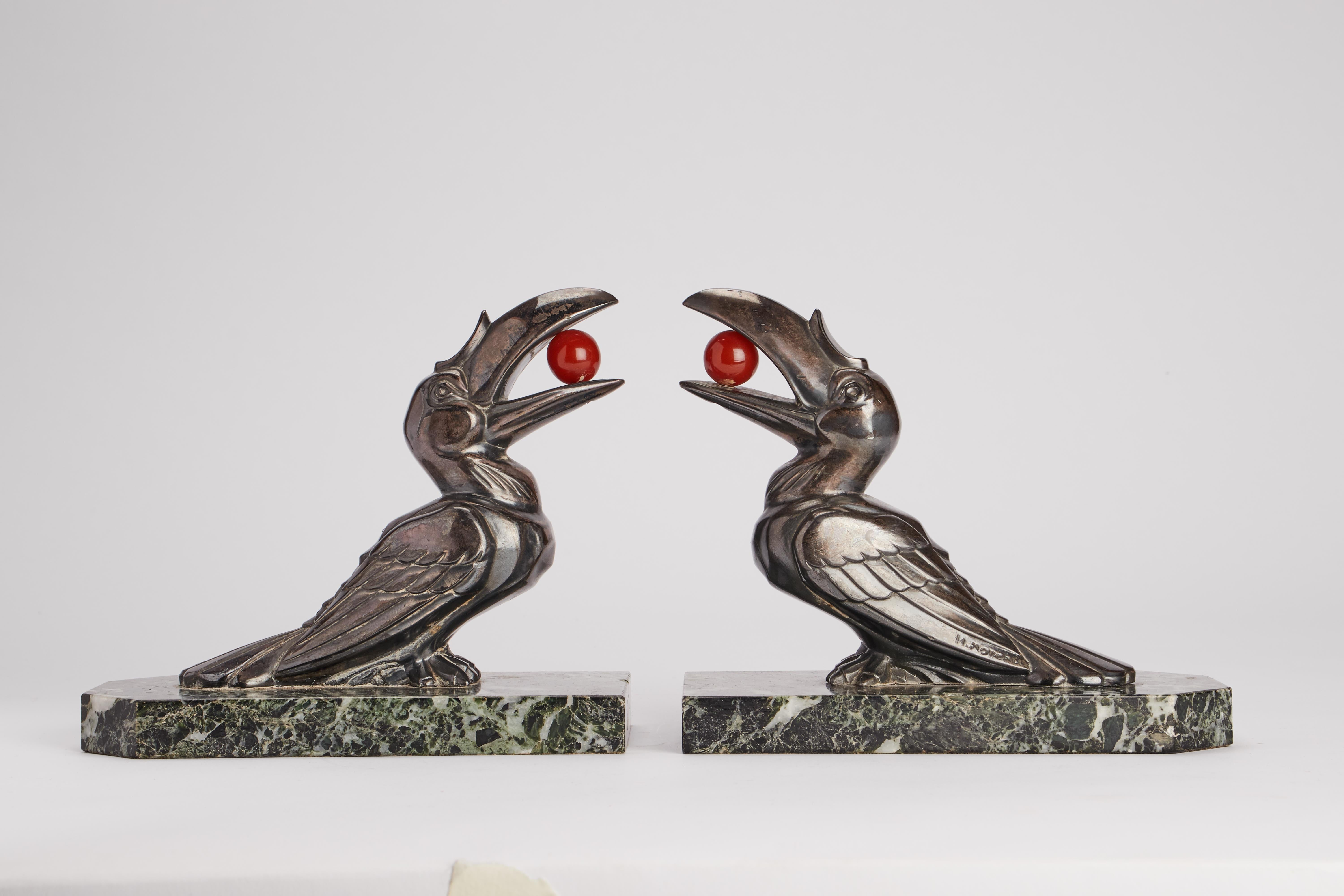 Pair of bookends in veined green marble with orthogonal structure. On the marble base there are two identical metal sculptures, depicting two Toucan birds with an amber ball in their beaks. Art Deco'. Signed H. Moreau. France circa 1925.