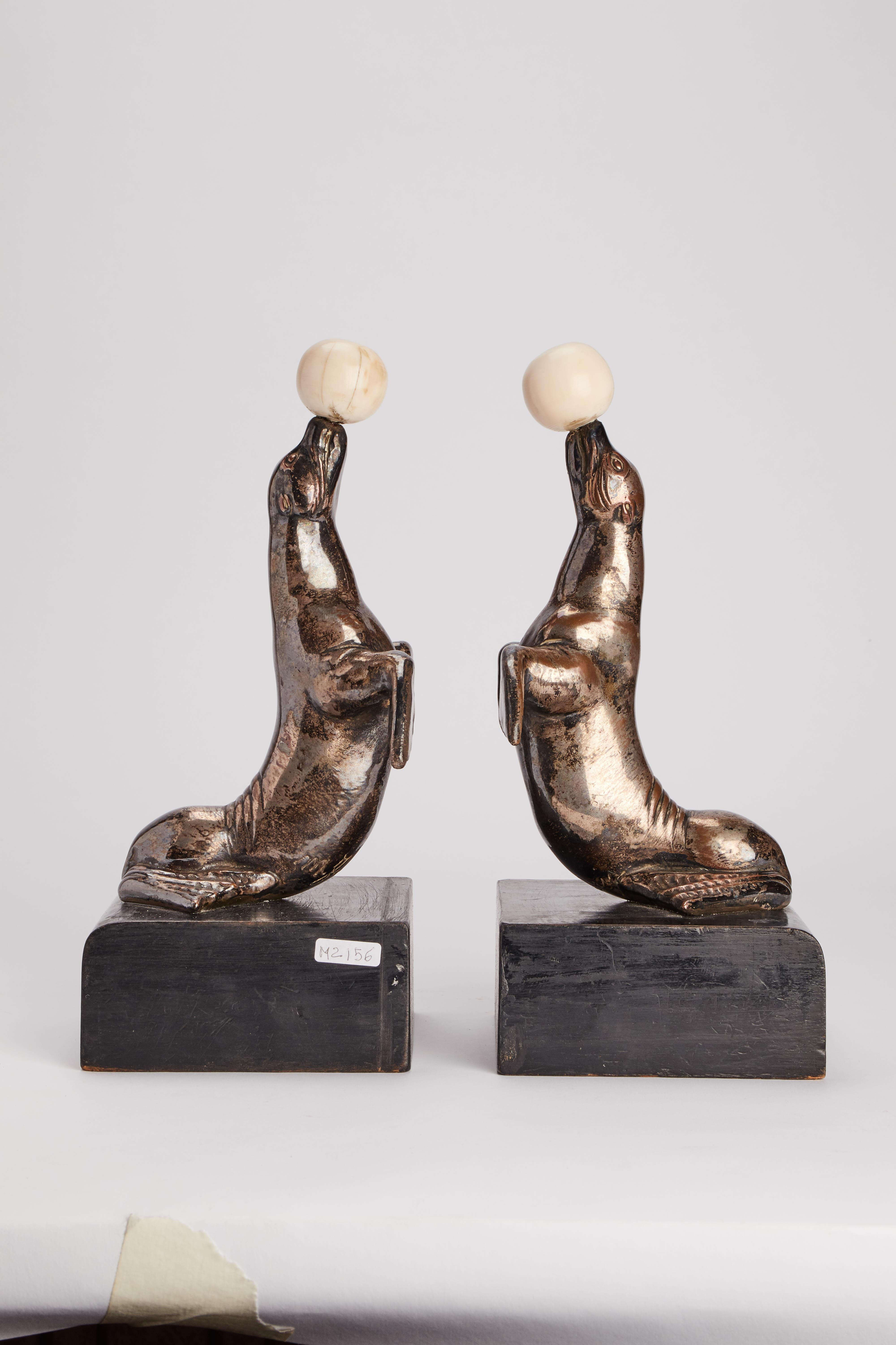Pair of Metal bookends representing two seals with an ivory ball on their muzzles. ebonized fruitwood base. Italy circa 1930. (SHIP TO EU ONLY).