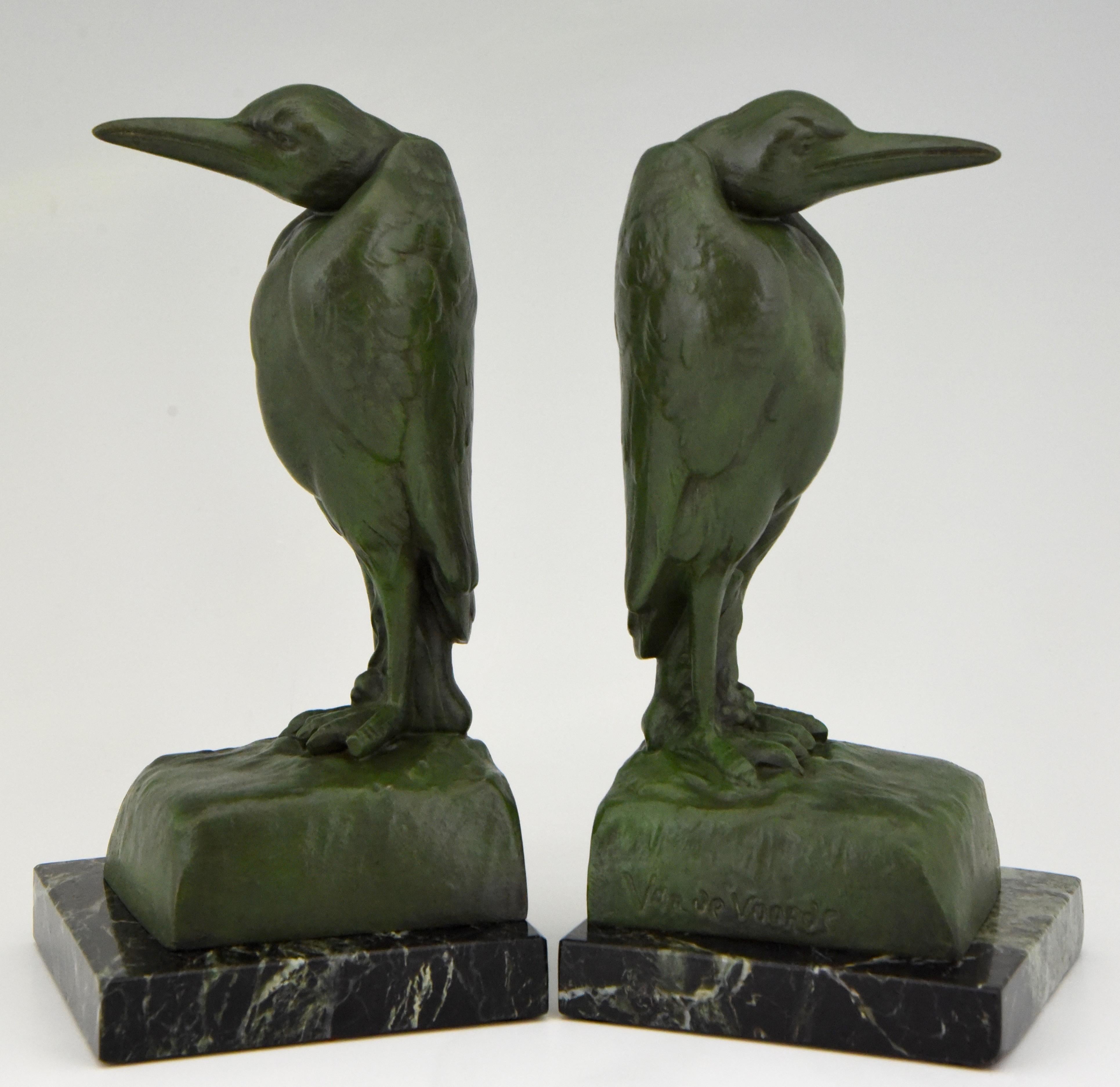A nice pair of Art Deco Marabou bookends by Georges Van de Voorde,
Belgian artist born in 1878 worked in France. 
The bird sculptures are in Art Metal with a dark green patina and are mounted on green marble bases. 
Signed and with foundry