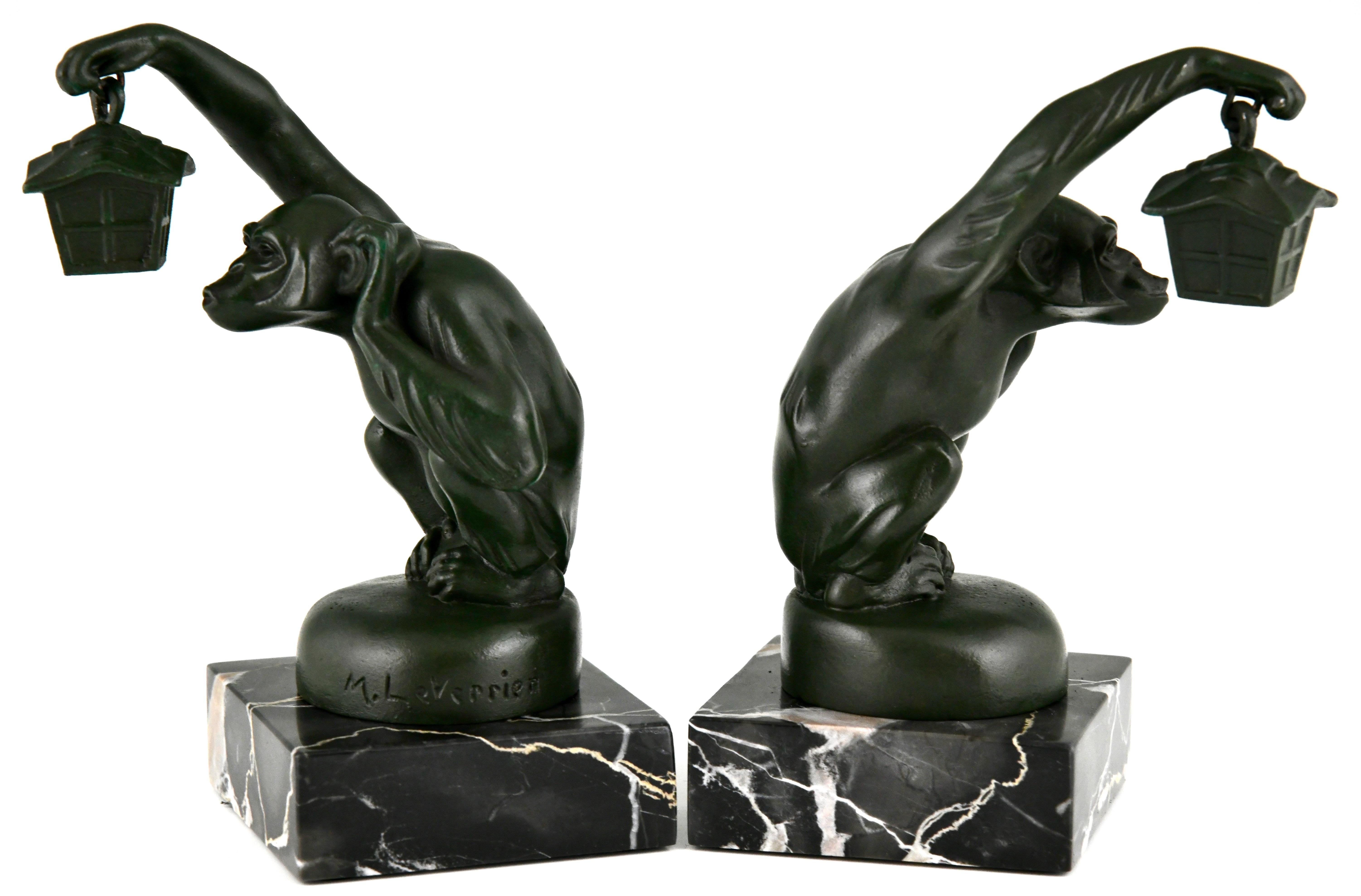 Art Deco bookends monkey with lantern by Max Le Verrier. 
Green patinated metal on a Portor marble base. France 1925. 
This model is called Boubou and illustrated in Mascottes automobiles, Michel Legrand, EPA éditions.