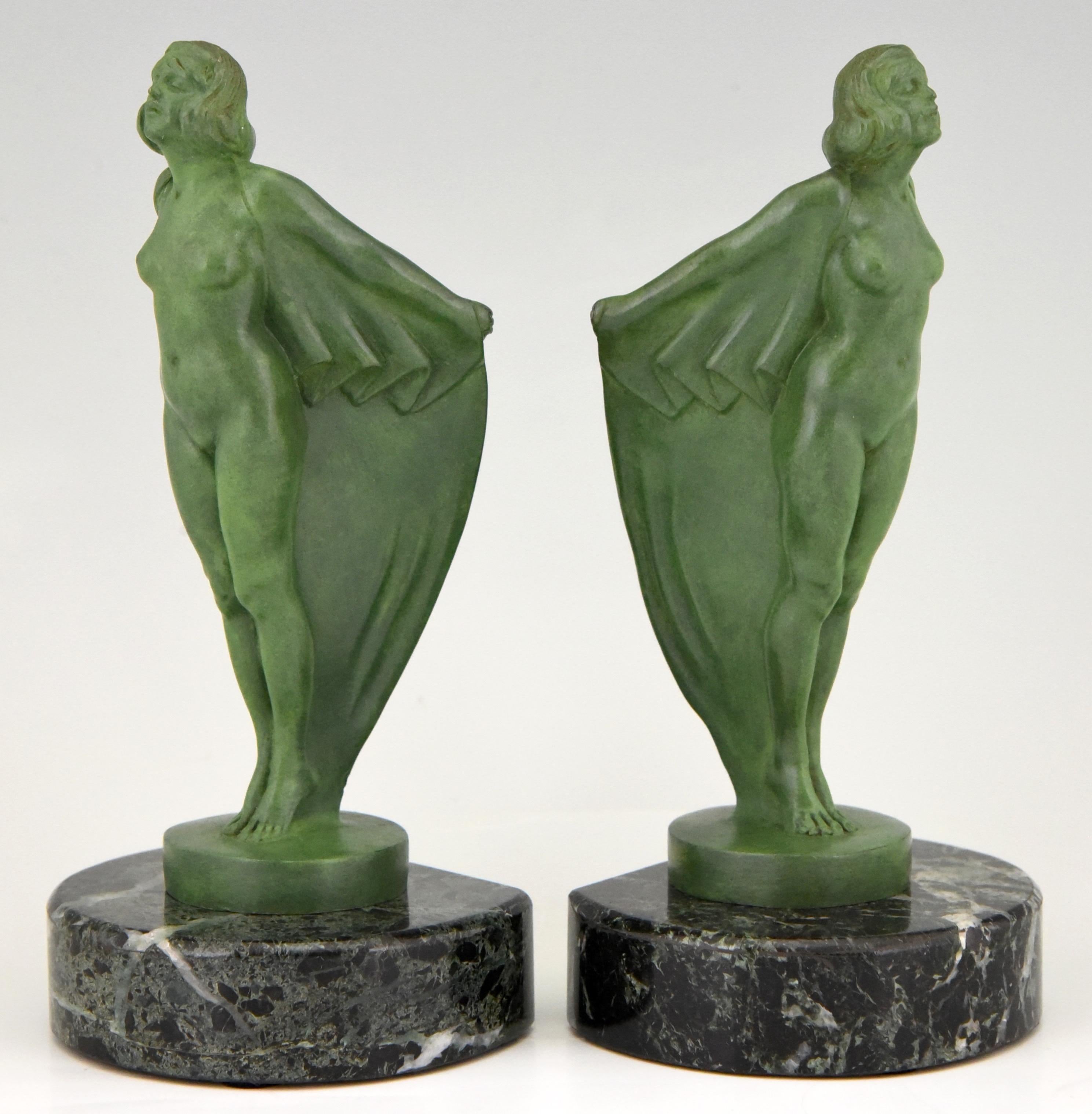 Art Deco bookends nude with cape by Max Le Verrier. The sculptures are executed in Art metal and have a lovely green patina. They are mounted on green marble circular bases. France 1930. 

This model was also designed as car mascot and is