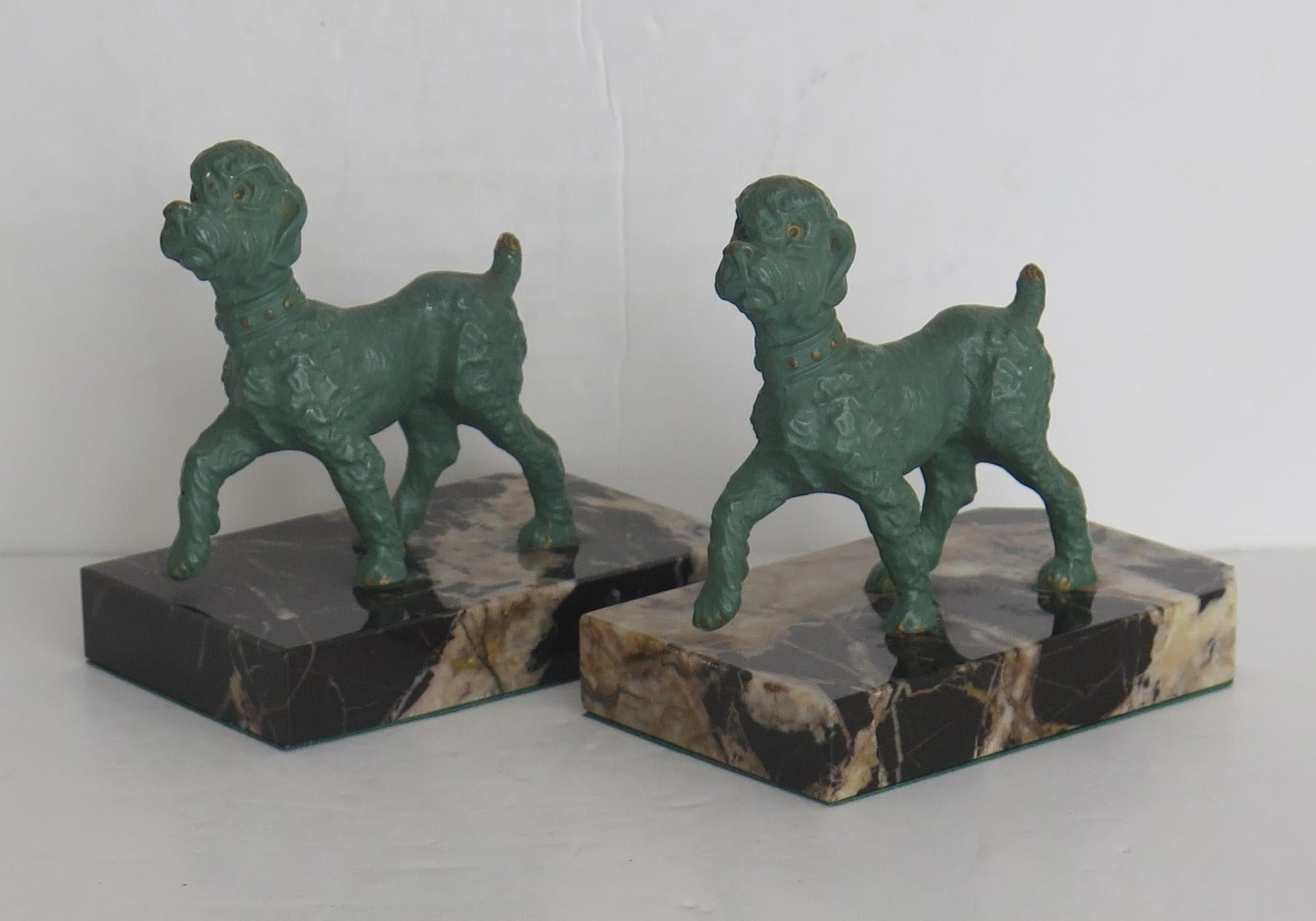 These are a beautiful pair of Art Deco period, Book ends of Poodle dogs on Portoro marble bases.

Each dog has been very well modelled with good detail. The dogs are made of spelter metal then cold painted by hand with a green finish having some