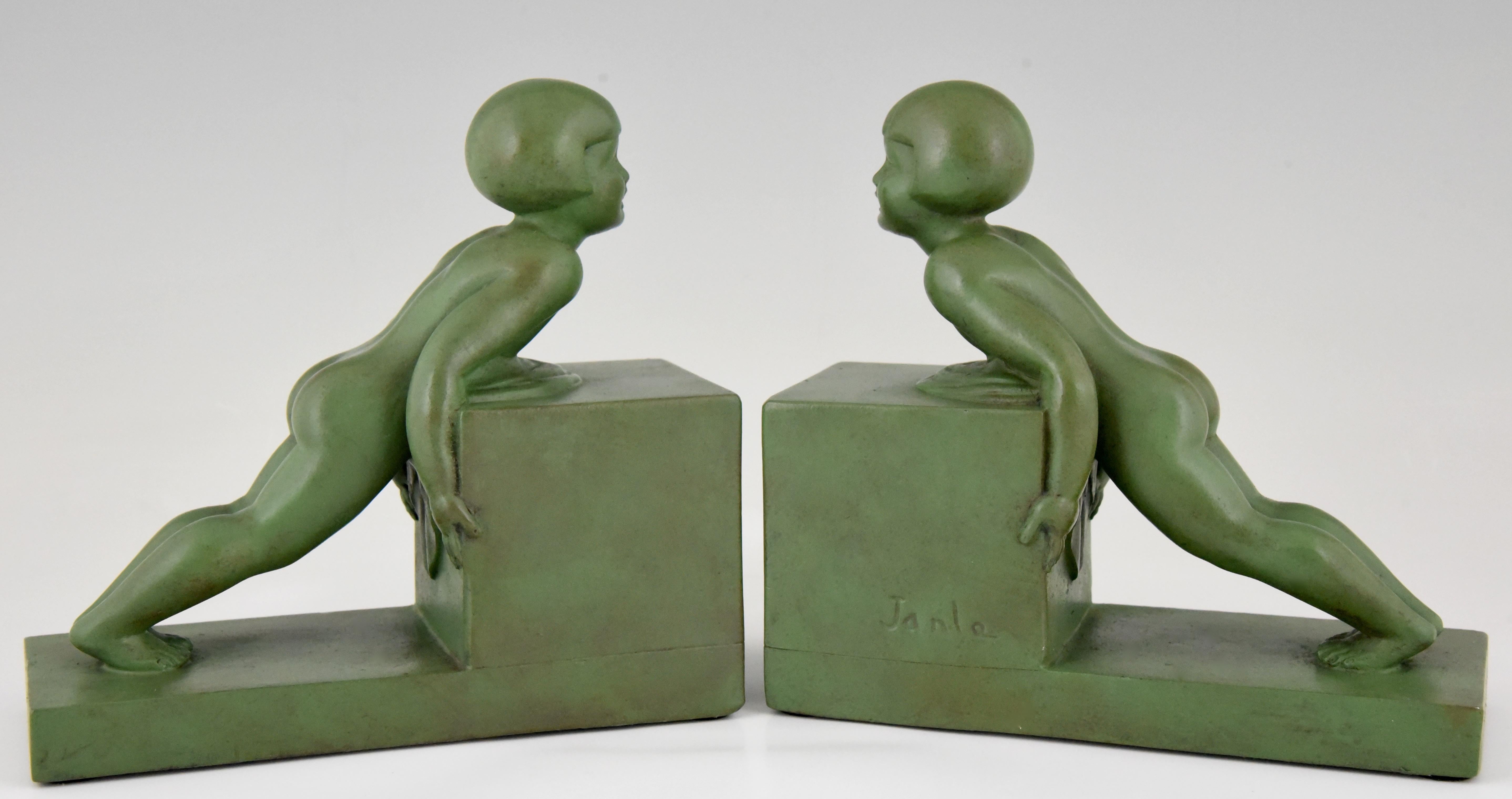 Cute pair of Art Deco child bookends picturing two little girls pushing a heavy cube. The sculptures are made of Art metal with lovely green patina. Signed by the French artist Janle, circa 1930.