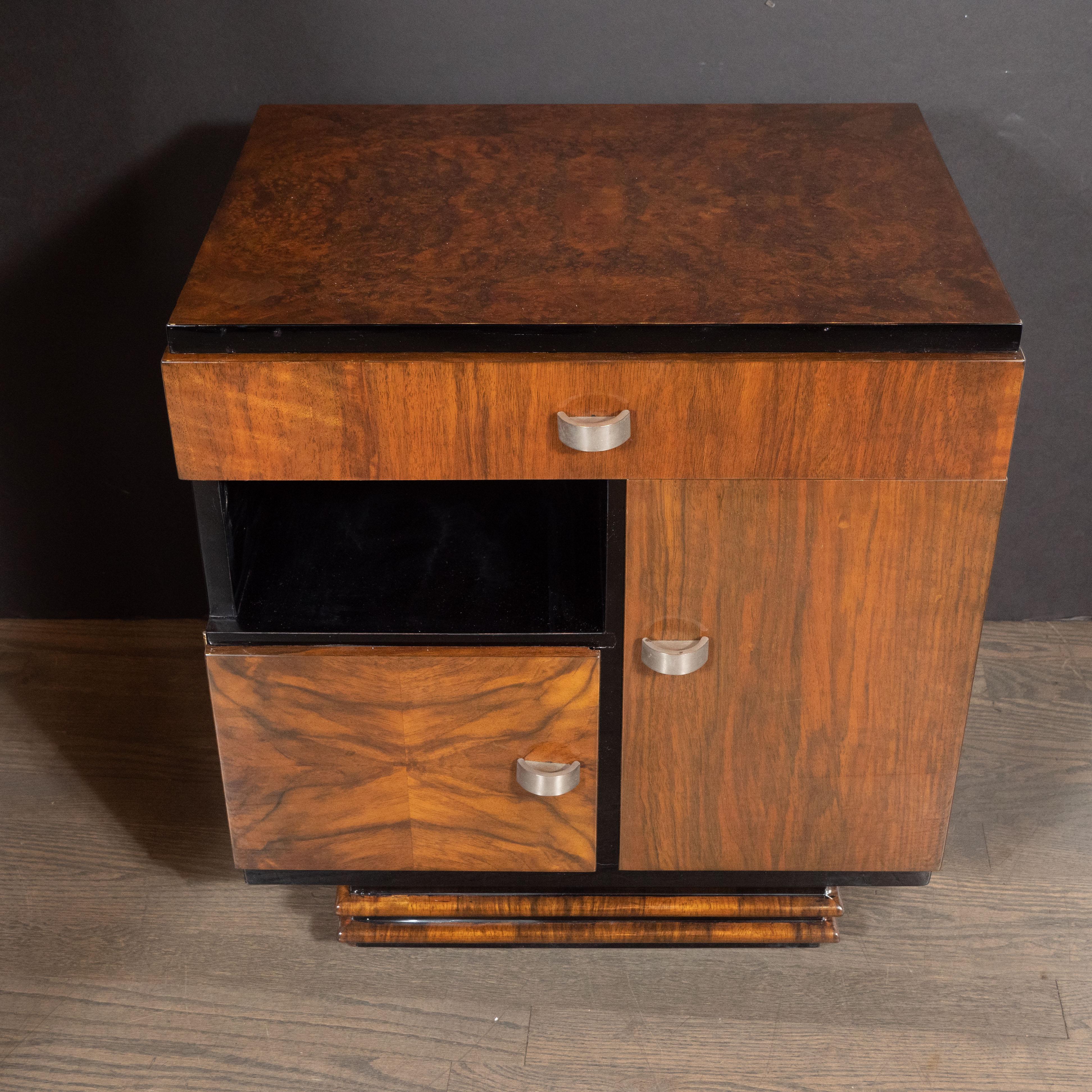 This stunning pair of Art Deco end tables/ nightstands were realized in France, circa 1930. Sitting on rectangular hind legs and a banded front, they offer volumetric rectangular bodies with a drawer at top with a two compartments and a cutout,
