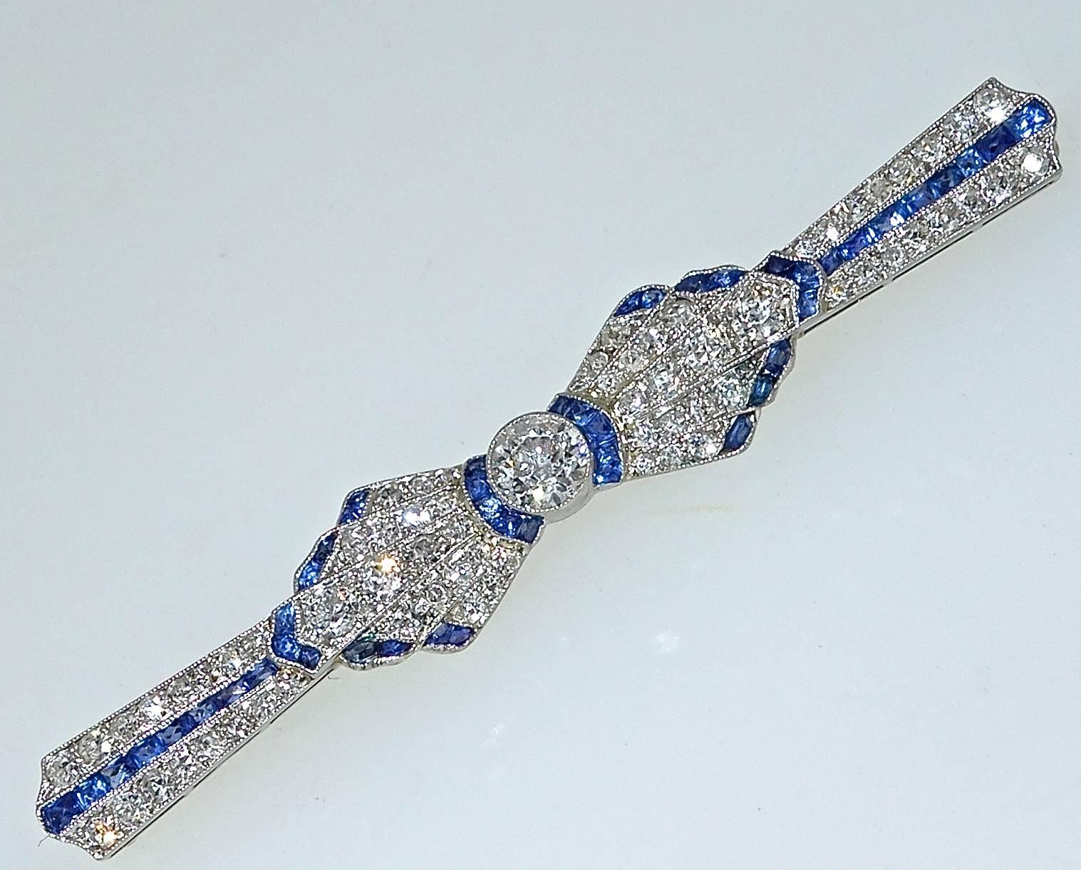 Platinum (with a gold pin stem), this brooch has fine diamonds and fancy cut fine blue sapphires.  The pin is 2.50 inches long and centers a .50 ct old cut diamond.  The 45 French cut fine natural sapphires are a bright blue and weigh approximately