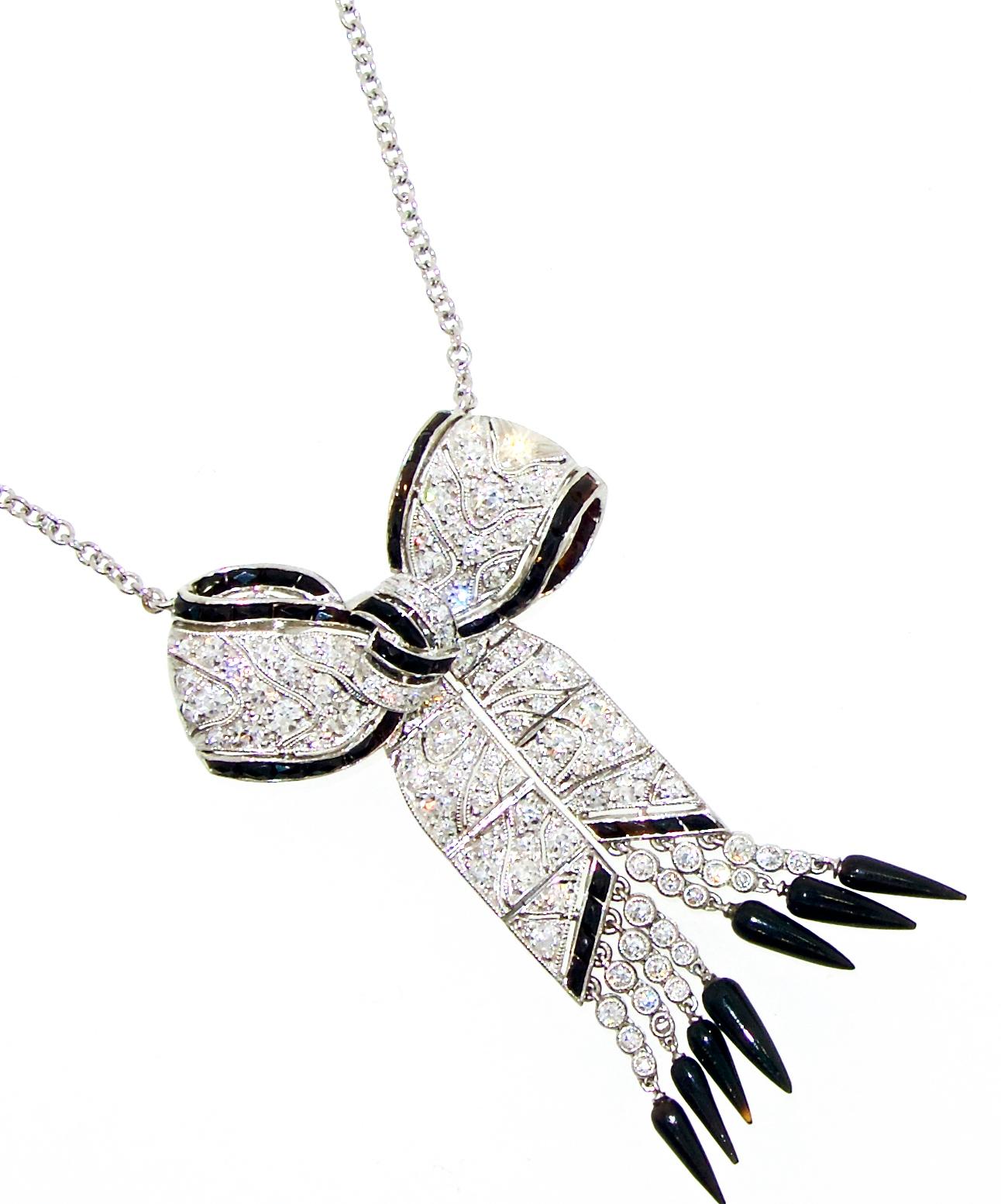 Platinum, diamond, onyx Art Deco necklace with fine white diamonds and fancy cut onyx.  The hanging elements are articulated, the platinum has a fine cut out design, the bow is 2 inches long and hangs from a 15 inch chain.  (This charming piece