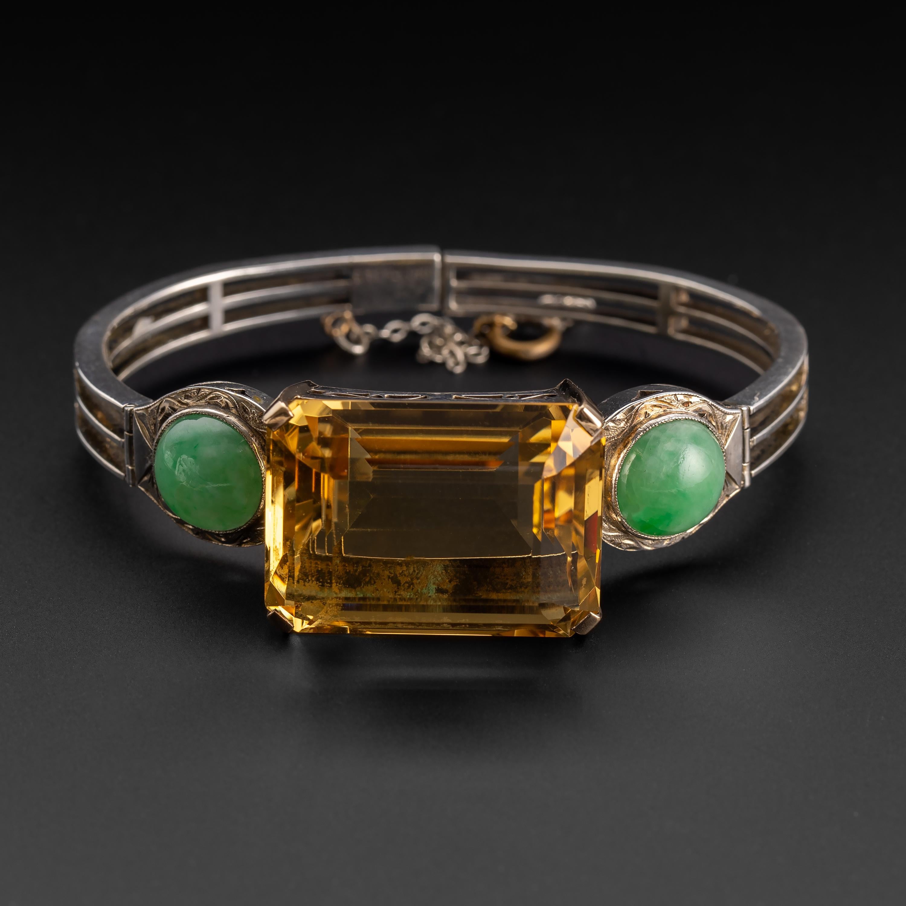 Created in silver and 14K yellow gold, this striking and unique Art Deco bracelet features an enormous 66-carat emerald-cut citrine flanked on either side by a pair of 11.5mm round cabochons of natural and certified untreated apple-green jadeite