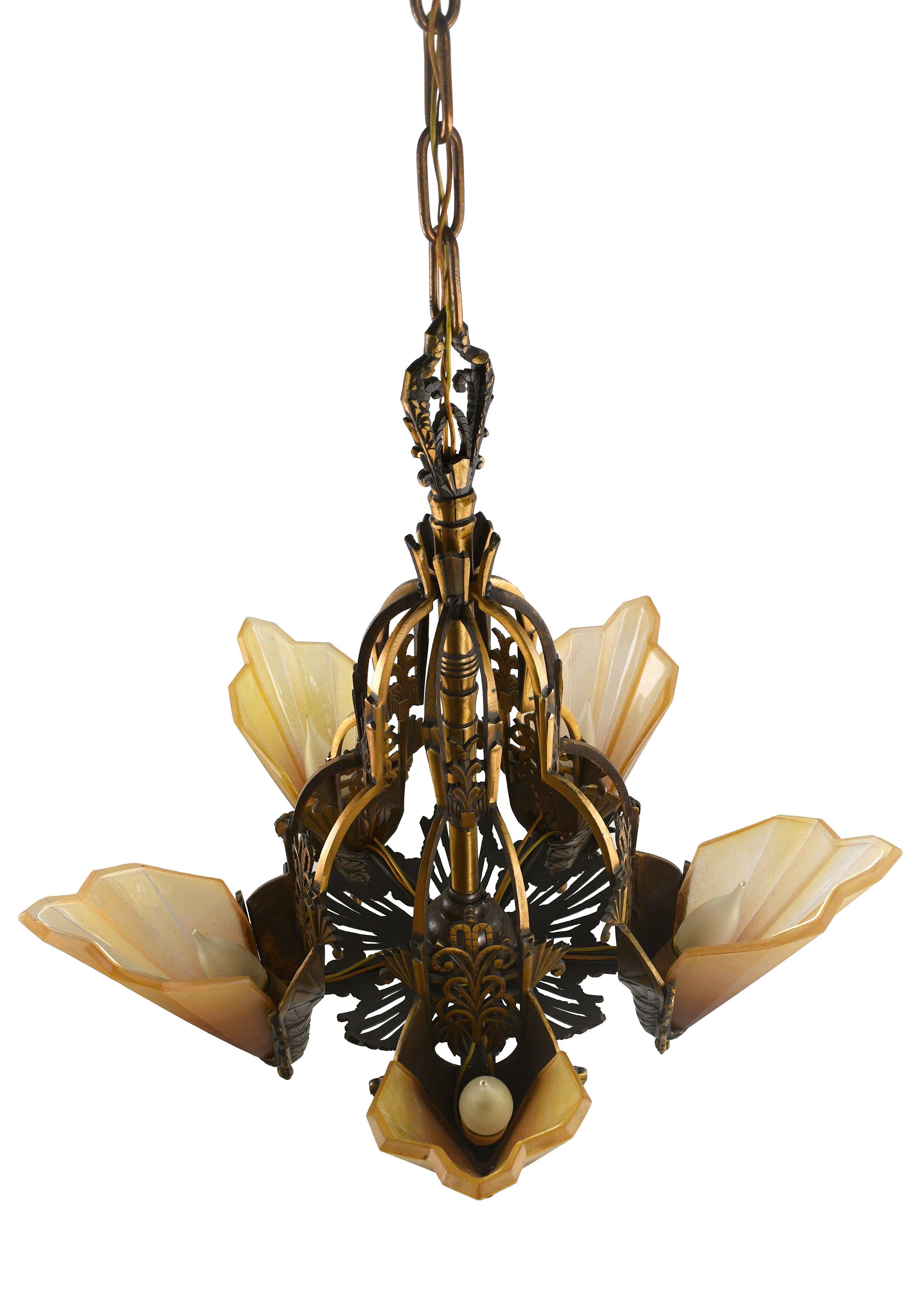 Intricately detailed 5 slip shade chandelier. This chandelier is made of lovely brass and features a geometric Art Deco design with a pleasant mix of sharp angles and curves.
