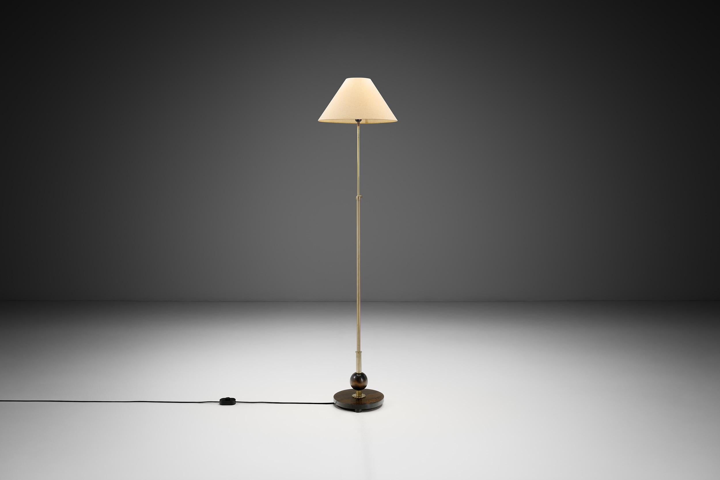 Il movimento Art Deco europeo degli anni '30 è stato un faro di innovazione e stile, e il periodo da cui è nata questa lampada da terra in ottone e legno. Questo squisito pezzo d'arte funzionale incarna l'eleganza e la raffinatezza che hanno