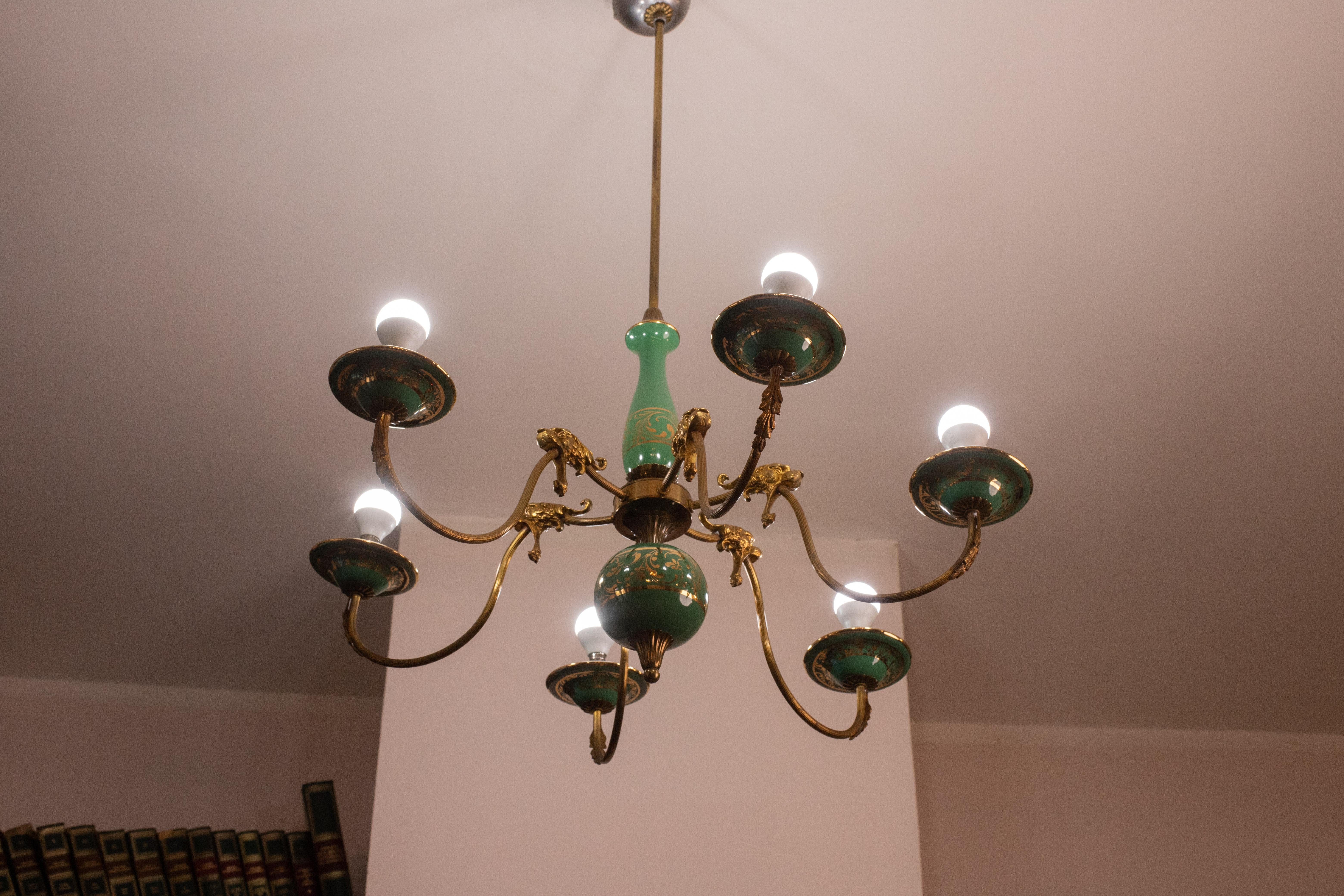 Stunning Art Deco chandelier made of brass and painted terracotta with decorations.

Each arm of the chandelier is ornamented with friezes refiguring lions.

The 6 light points mount a European standard e 14 socket.

All elements of the