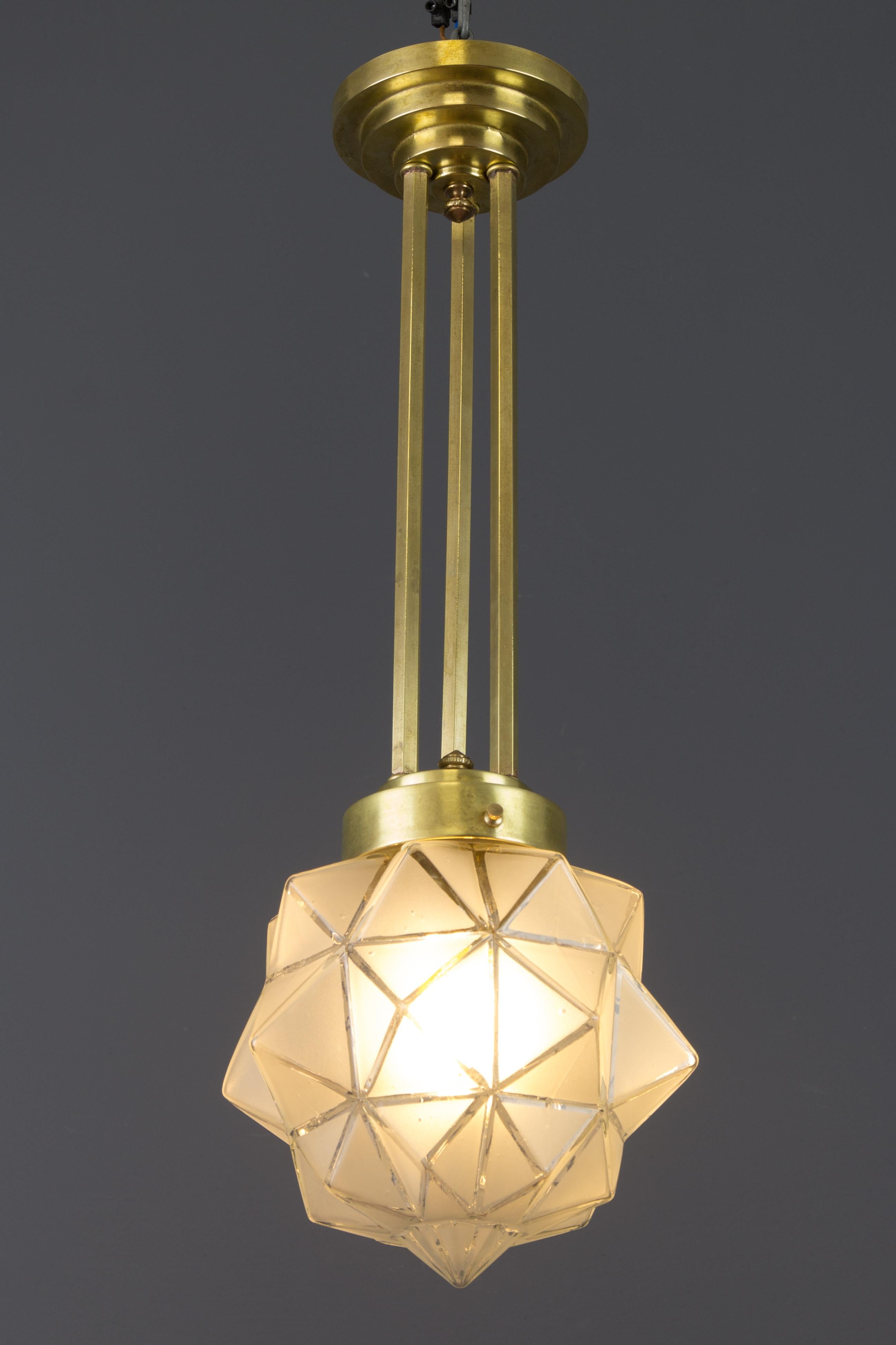 Elegant Art Deco pendant light fixture made of brass with beautifully geometric, polygonal-shaped frosted glass shade. Made in France, in the 1930s.
One socket for a B22-size light bulb.
Dimensions: height 52 cm / 20.47 in; diameter 19 cm / 7.48 in.