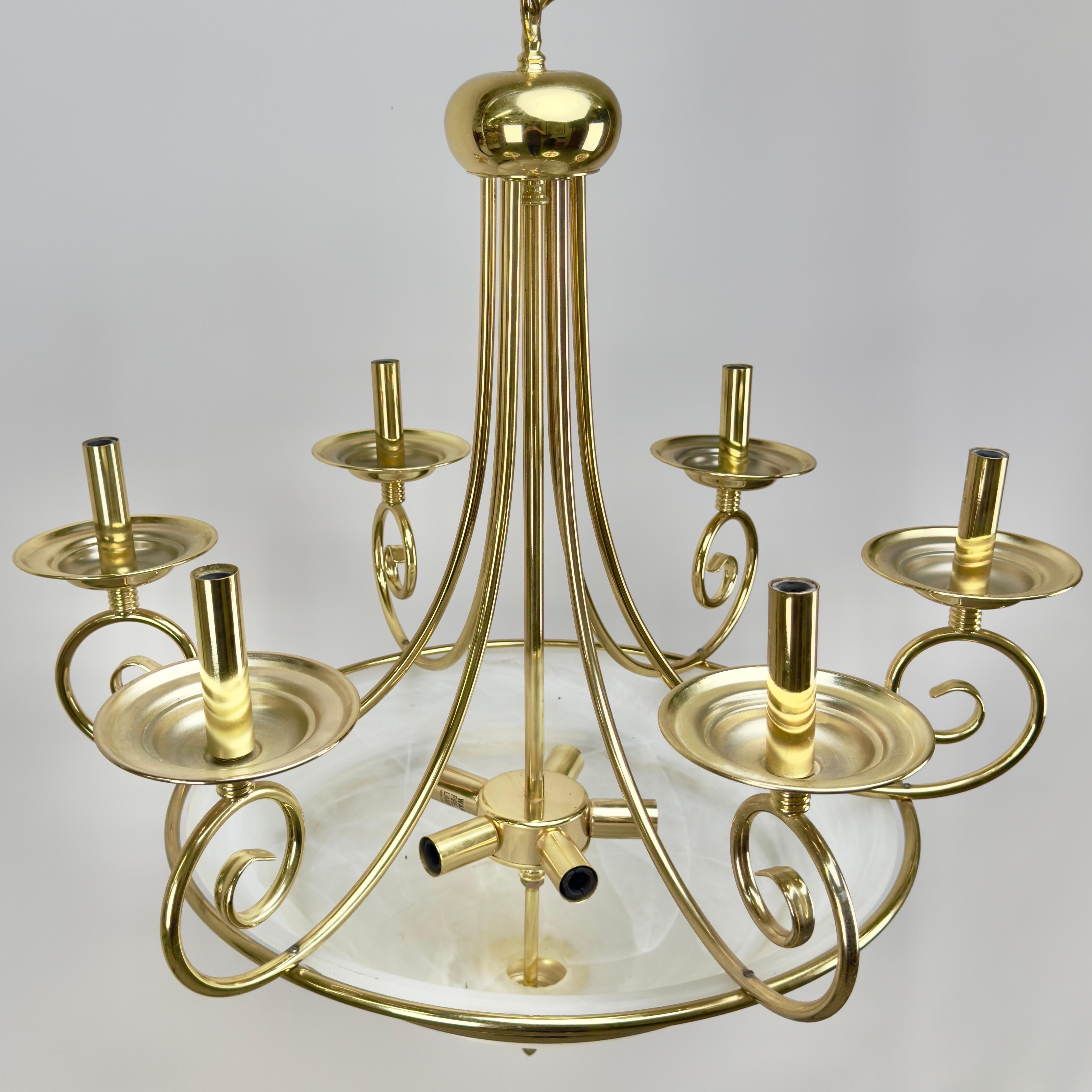 Questa splendida struttura di lampadario in ottone Art Déco è caratterizzata da sei graziosi bracci in ottone, ognuno dei quali si estende verso l'esterno con una curva fluida e ampia, terminando con dei portacandele / Bobeches. Il design vorticoso