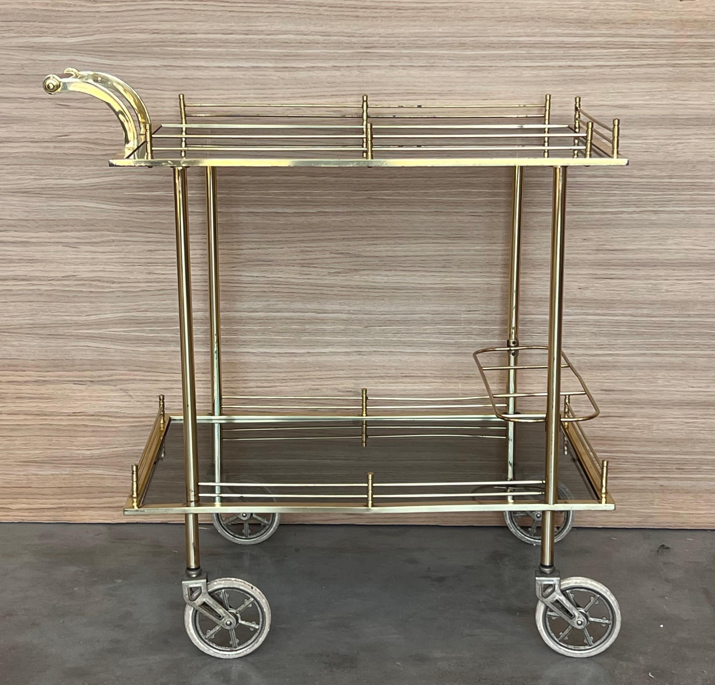 Fabuleux chariot de bar en laiton avec verre fumé
Mettez fièrement en valeur vos plus belles carafes et verres à pied ! Poignée en laiton. 
 Cette pièce est en très bon état d'origine et montre qu'elle a été bien entretenue.

Hauteur de l'étagère