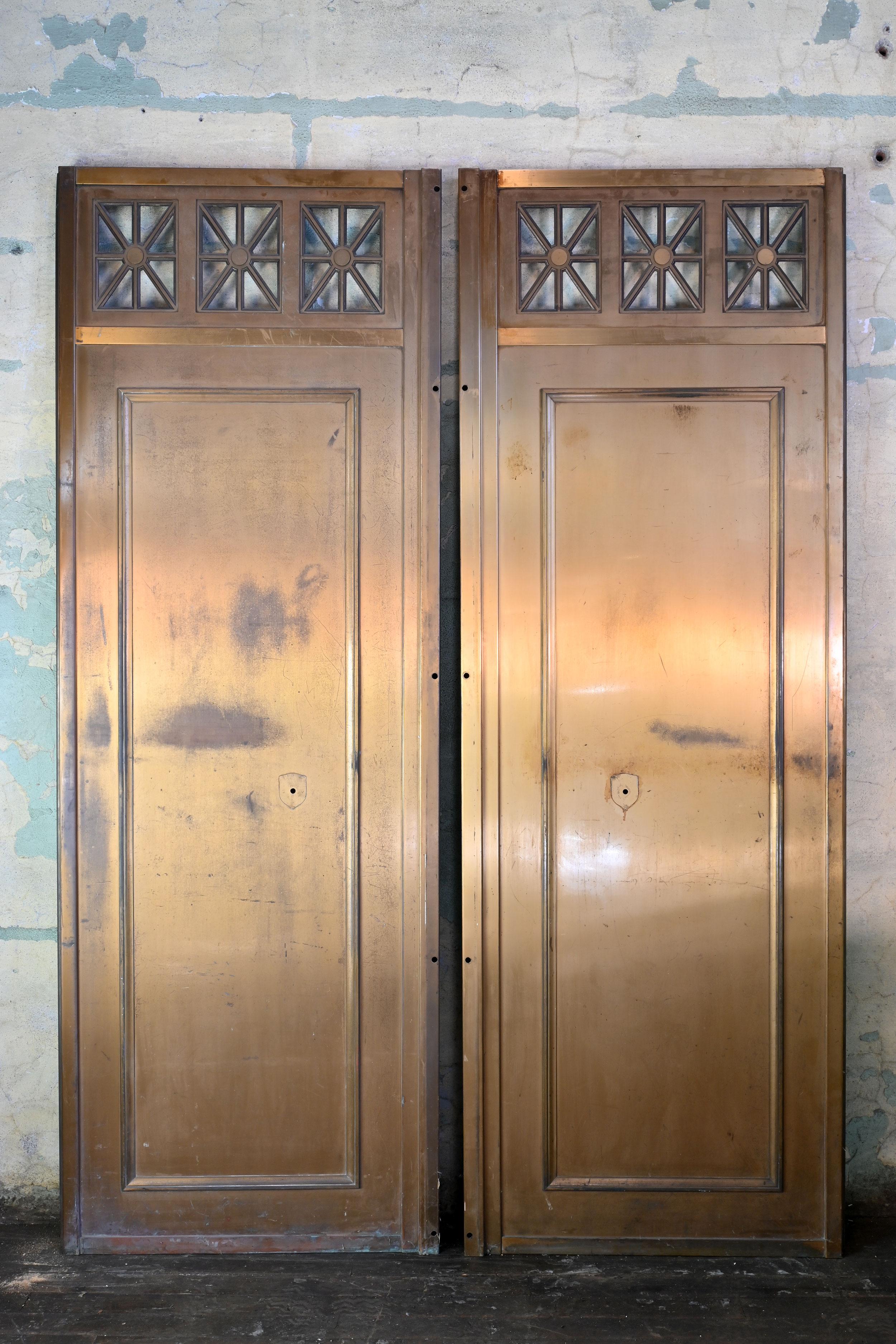 These elevator doors are a wonderful piece with great brass patina. They feature top vents with geometric deco styling and have a mounting space for brass backplates, no longer a part of the piece. Similar holes in the edges are where there once was