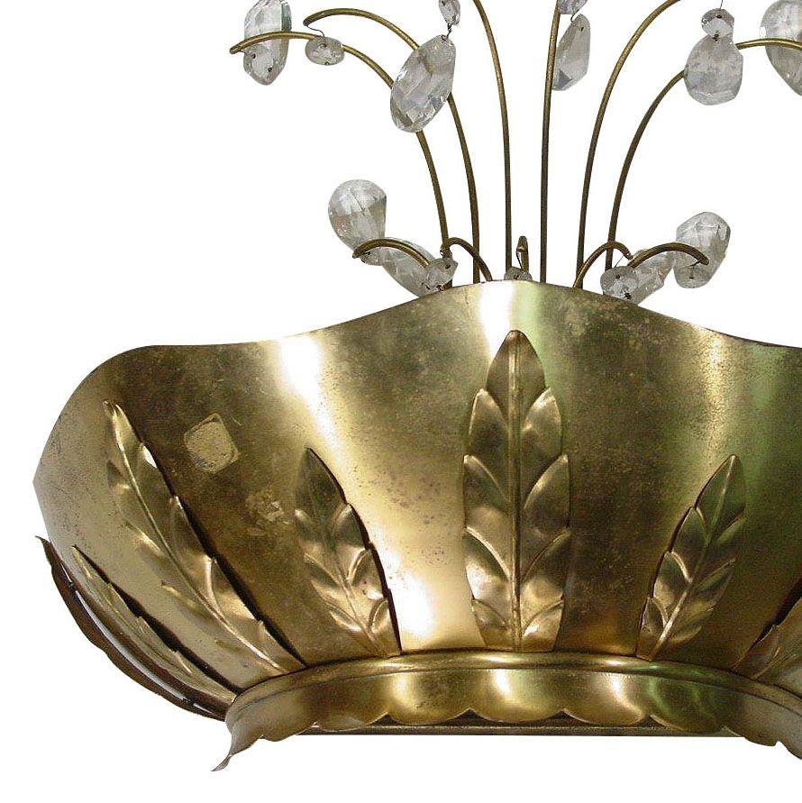 Ein Paar Art-Deco-Wandleuchter aus Messing mit dekorativen Armen und Zierkristallen. Die handgefertigte Schale aus Messing mit geprägten Palmblattmotiven reflektiert das Licht von der offenen Oberseite und dem unteren Glasschirm wunderschön und