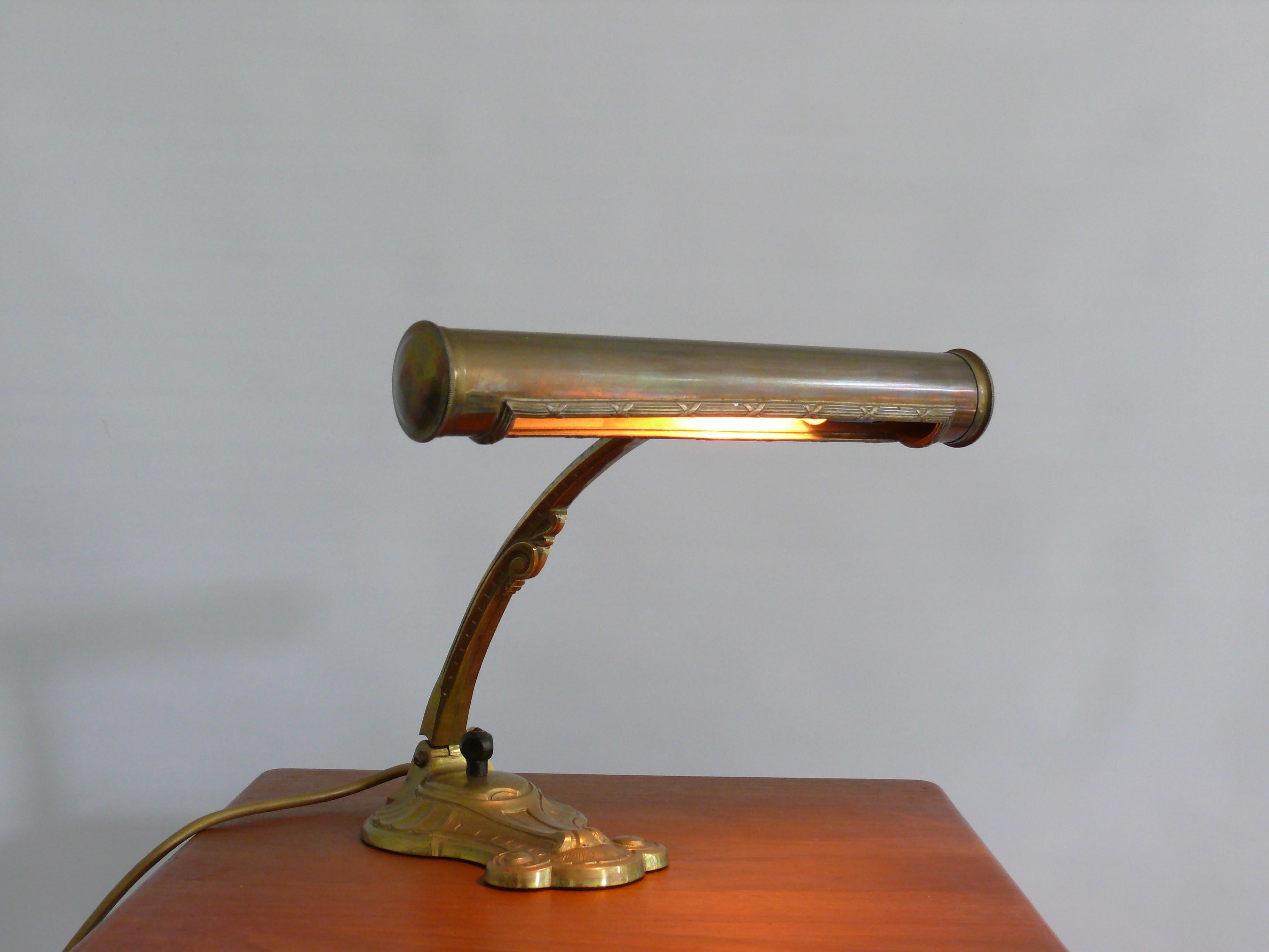 Extraordinary Art Deco piano lamp/table lamp, probably from the 1930s with an ornate shade opening and curved base. The lamp is made of brass and has a heavy base. The lampshade can be tilted and locked using a wing screw - left-hand thread! The