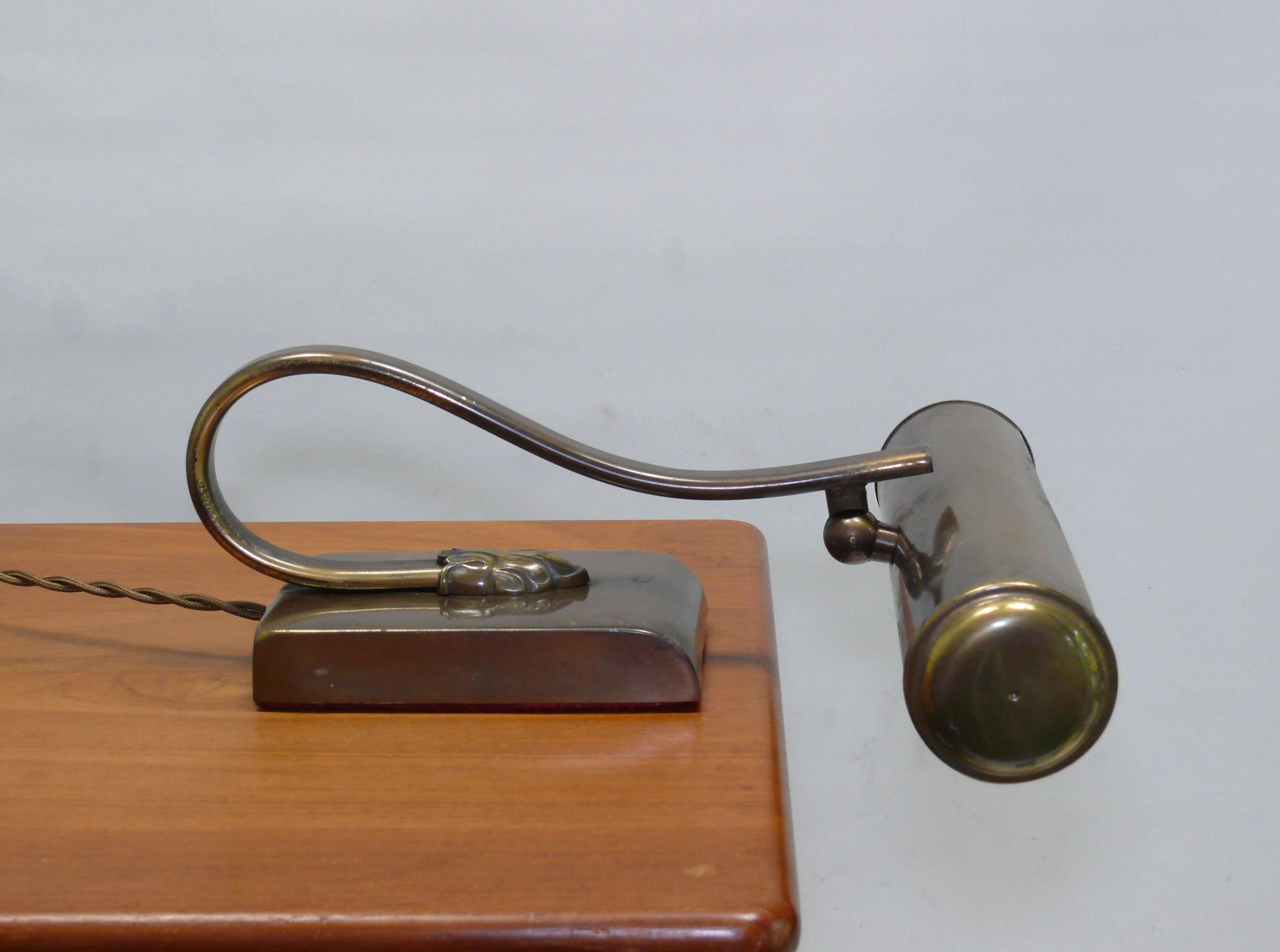 Piano lamp in Art Nouveau style, probably from the 1930s - 1950s. The lamp is made of burnished brass with a heavy metal base. The shade can be adjusted, the arm is fixed, therefore only used as a piano light. The light is switched on and off using