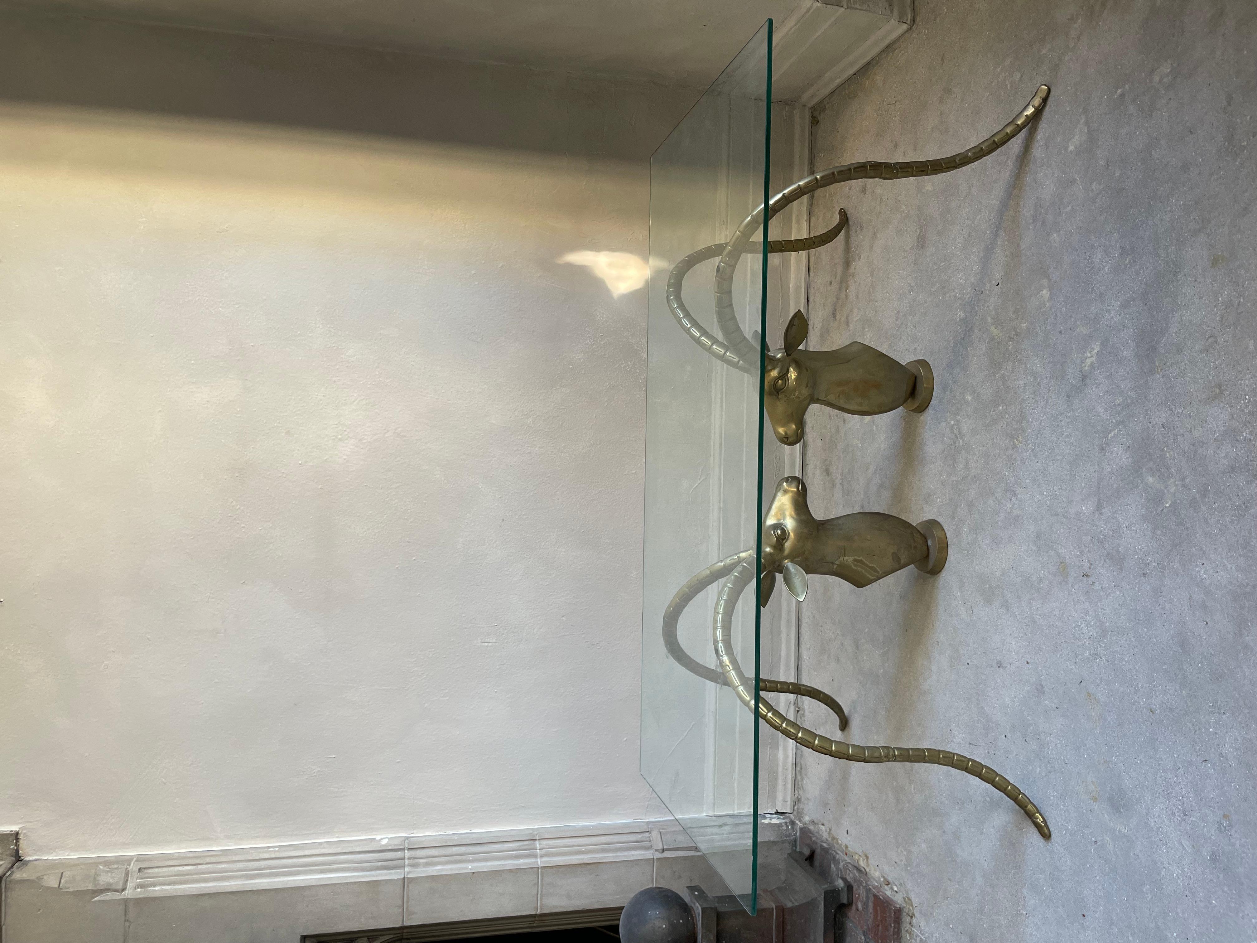 Gorgeous Art Deco table featuring large ram busts with elongated antlers. Base is made of solid brass showing a gorgeous and natural patina from use over time. A true statement piece that will surely turn heads and start many conversations.

In