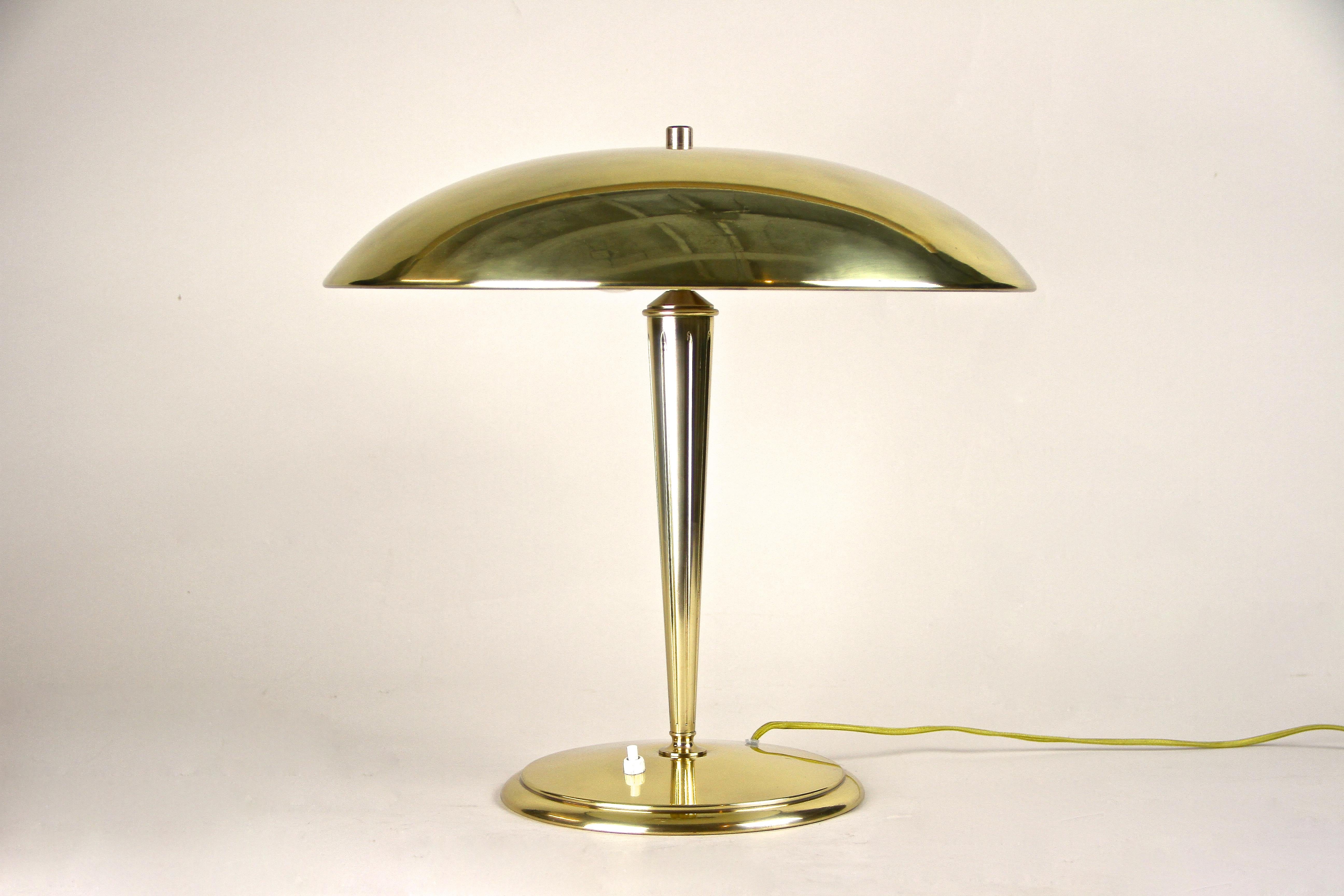Brass table lamp from the Art Deco period in Austria around 1920. An exceptional lightning piece that comes in perfect restored condition and impressing with its absolutely outstanding design. The beautiful mushroom-shaped lampshade sits on an