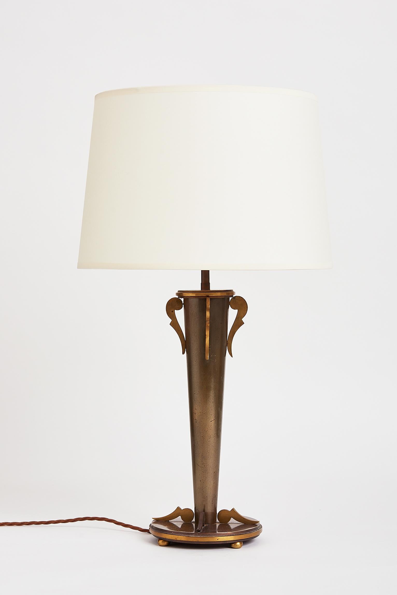 An Art Deco brass and gunmetal table lamp.
France, circa 1930.
With the shade: 63 cm high by 36 cm diameter.
Table base only: 44 cm tall by 16 cm diameter.