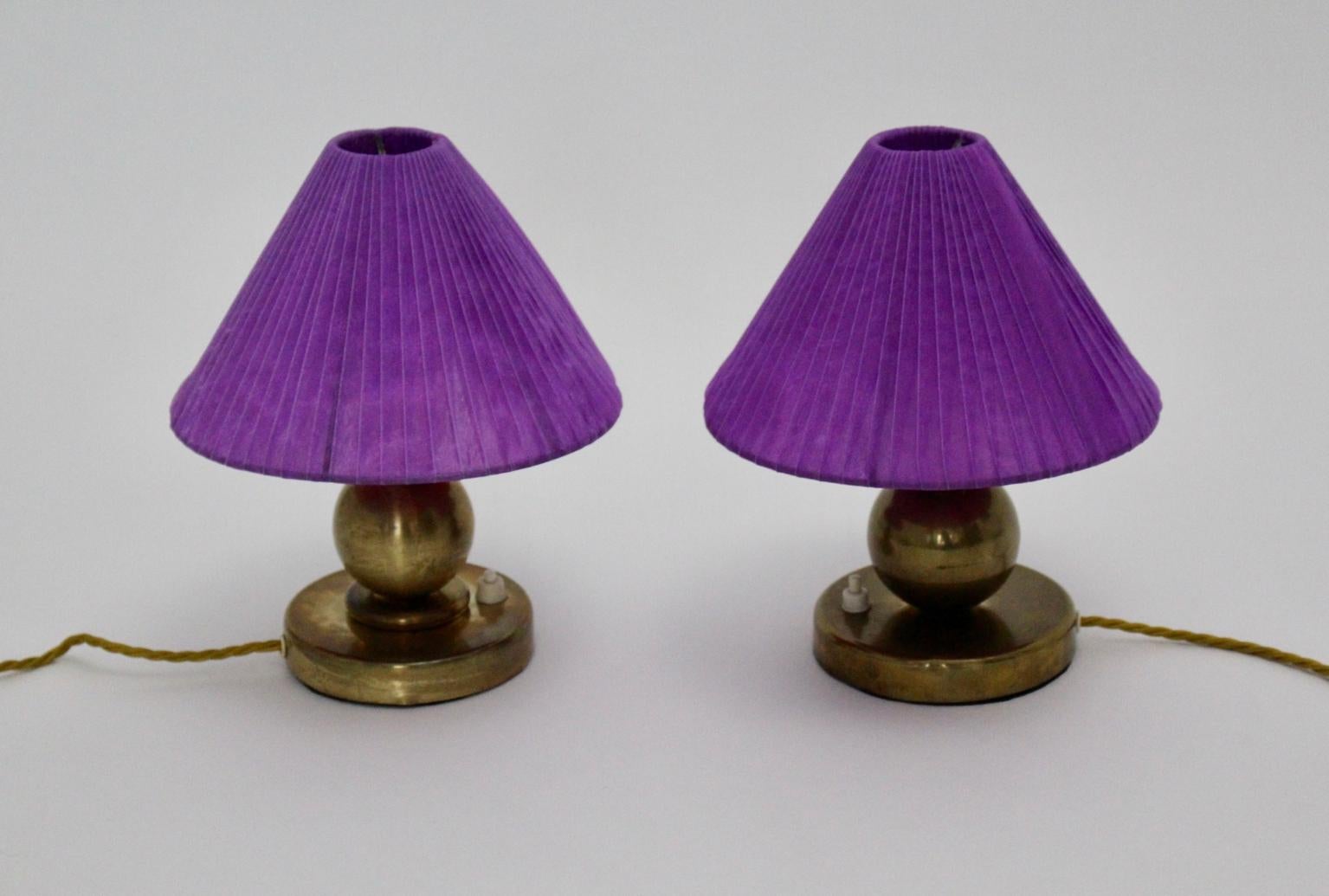 This presented pair of brass Art Deco vintage table lamps or bedside lamps shows a brass base and a renewed delicate organza fabric lamp shade colored in bold lilac.
The brass bases are in very good vintage condition with minor signs of age and both