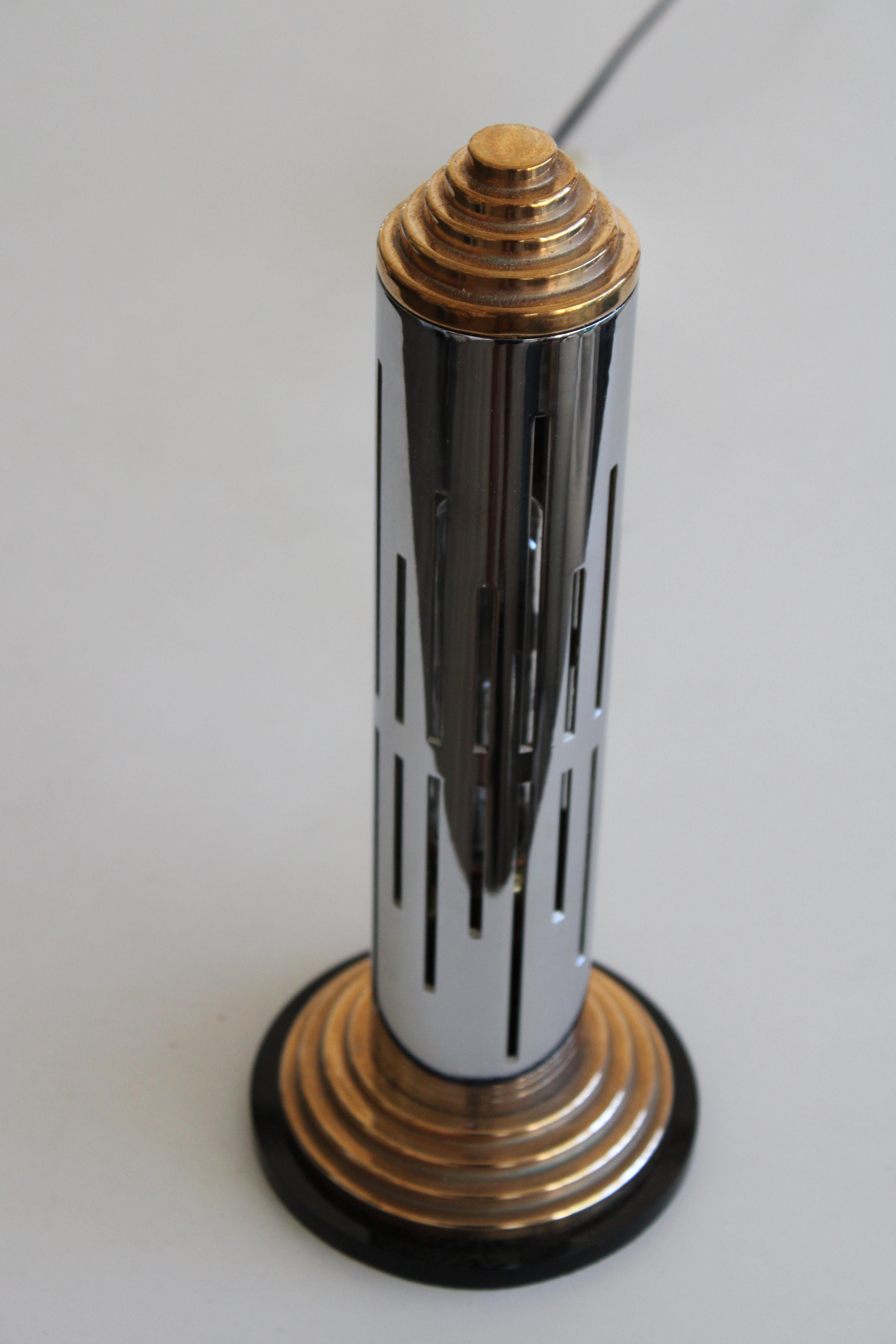 A streamlined Art Deco tower lamp with vertical slot openings where light emits. Black lucite disc supports a solid bronze stair-step base, chromed steel tower and solid bronze top. Lamp is rewired with an in-line dimmer switch. Lamp measures 12