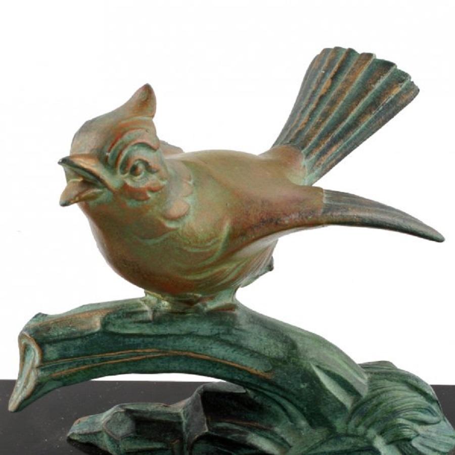 An early 20th century cold painted Art Deco bronze figure of a bird.

The bird is modelled standing on a branch with it's wing flapping and it's beak open.

The bronze is mounted on a black marble plinth which has yellow figured marble shaped