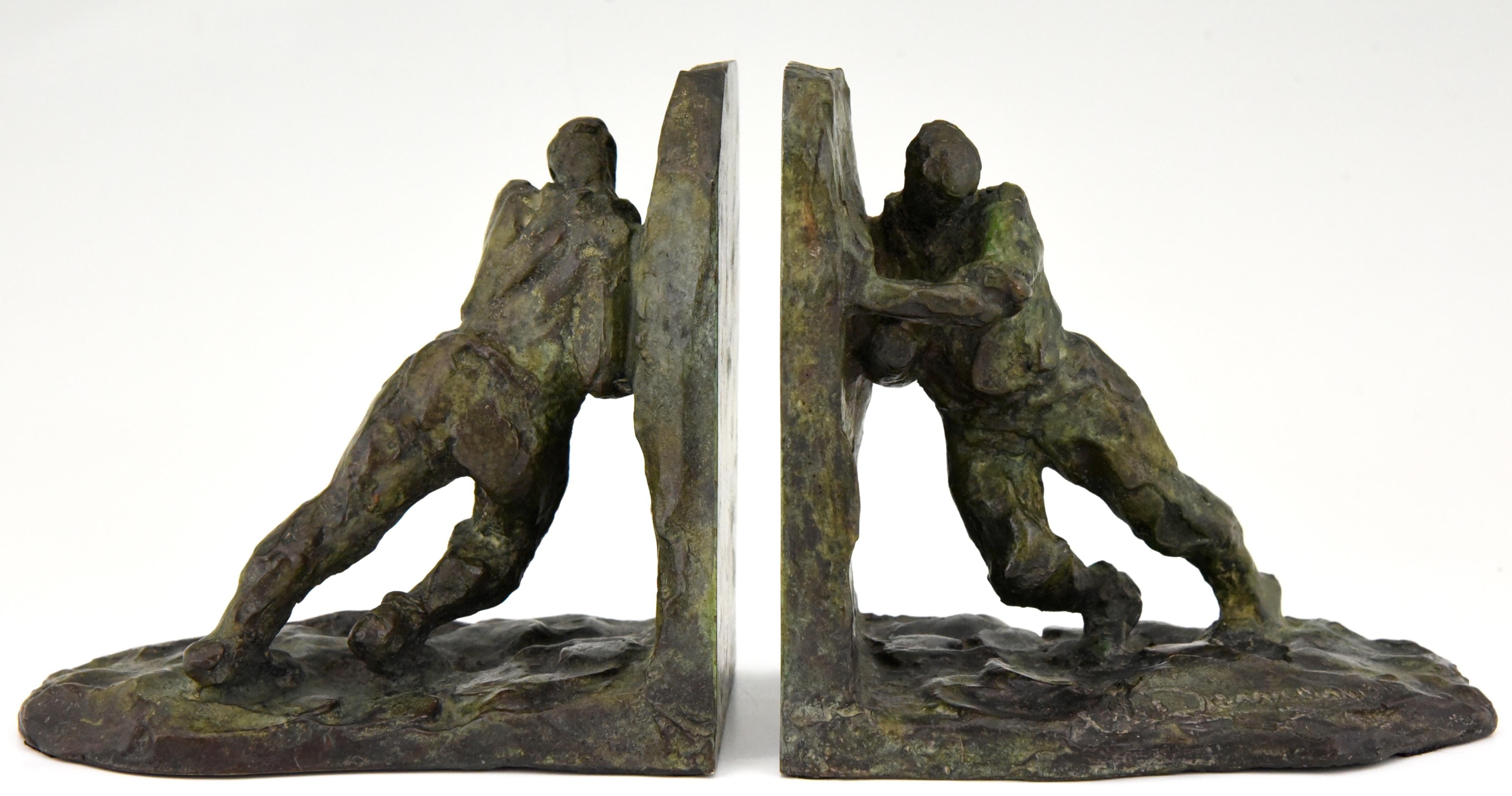 Art Deco bronze bookends picturing two men pushing, France, 1925. 
Signed by the well known sculptor Victor Demanet.
The artist was born in 1895 and worked in Belgium and France. 
The bronzes have a lovely green patina with lighter shades.