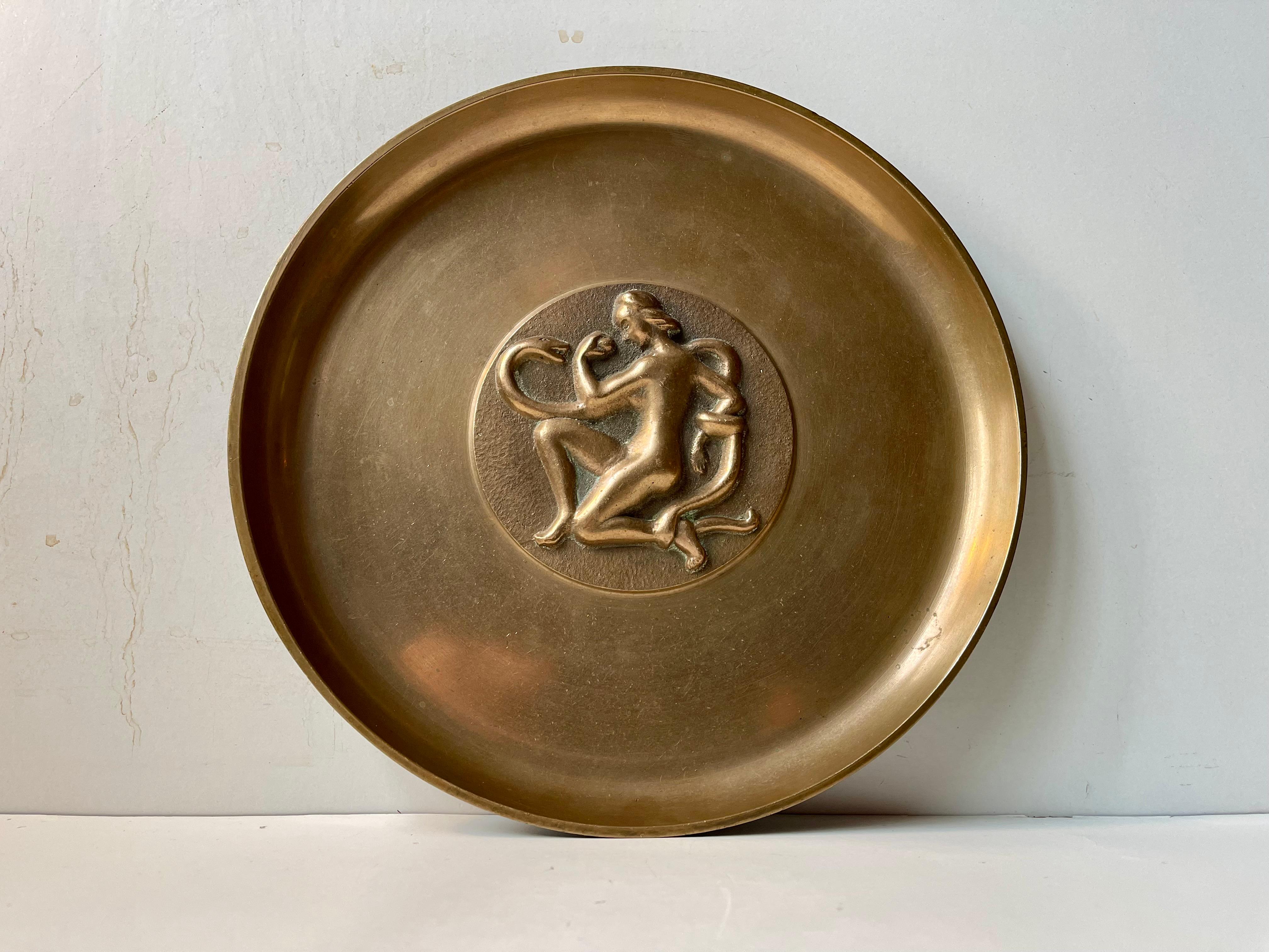 A perfectly balanced and with a soft yet tactile sense this heavy shallow bronze bowl, charger dish or tray demands the right kind of attention.  With its raised/relief center-motif of naked Eve holding an apple and entangled by the large serpent