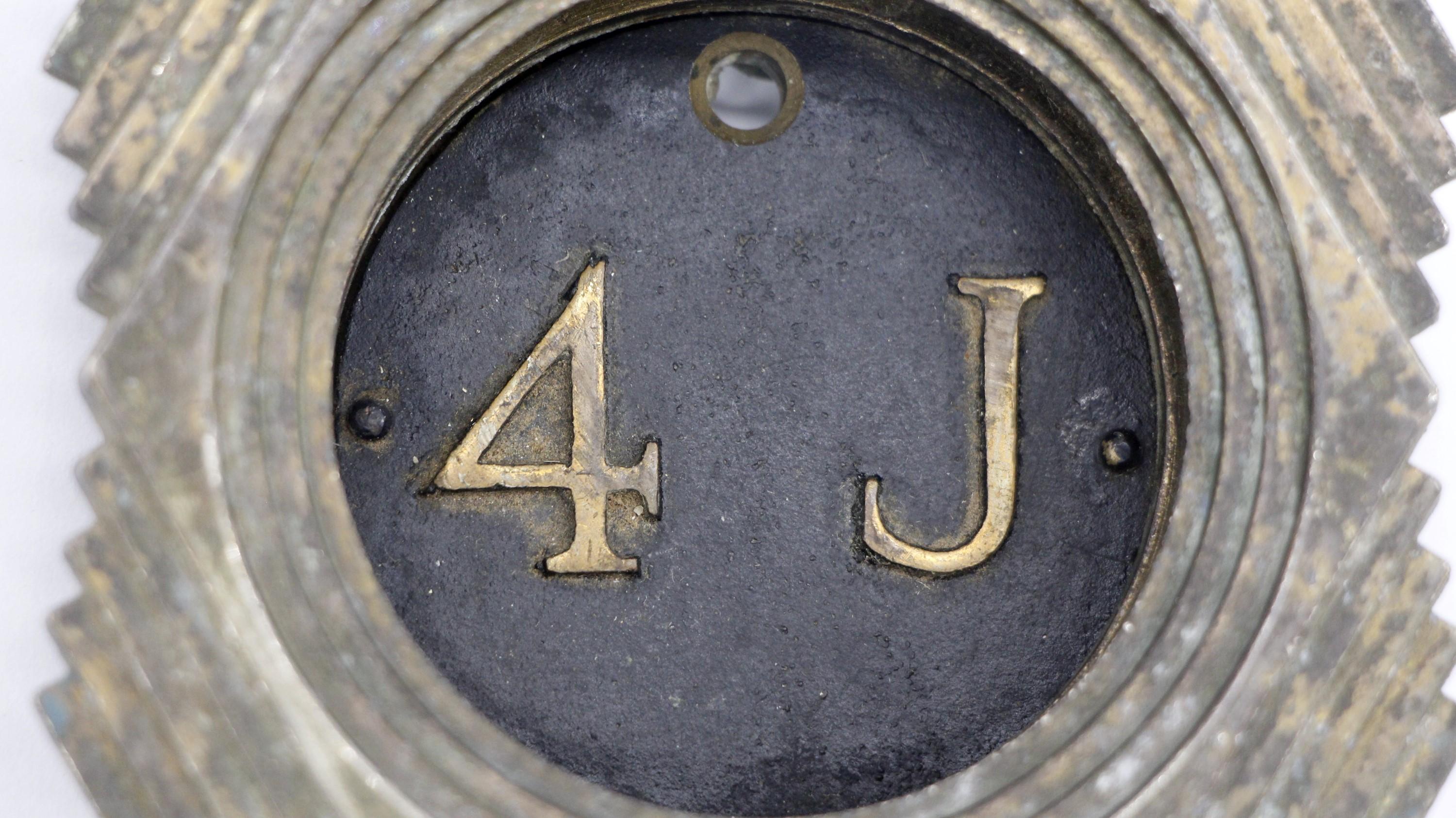 1928 cast bronze Art Deco design hotel room or apartment peep hole manufactured by George W. Ackerman, Inc. Patented 1928. 4J stands out on a black circle center with a bottom name label slot. This can be seen at our 400 Gilligan St location in