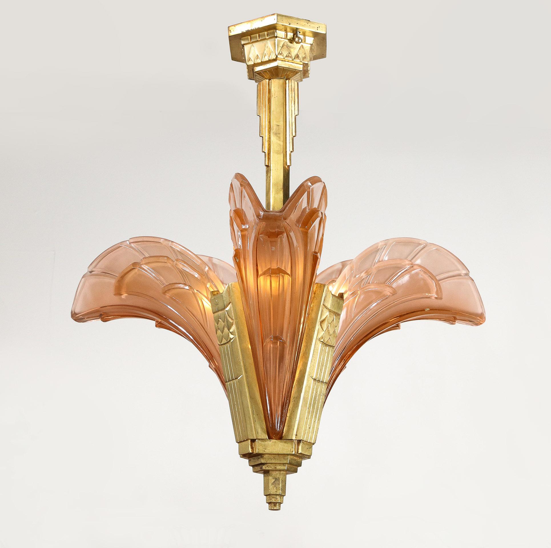 Le lustre art déco français a un cadre en bronze doré moulé supportant 3 abat-jours en verre rose pâle moulé. Chaque signature : ESG 1095 France