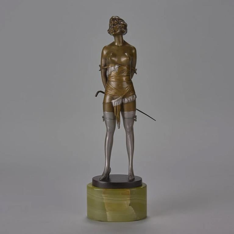 An erotically charged early 20th century Art Deco cold painted bronze figure of a seductively dressed young lady holding a riding crop behind her back standing in a domineering pose and wearing a revealing basque with gartered stockings, raised on